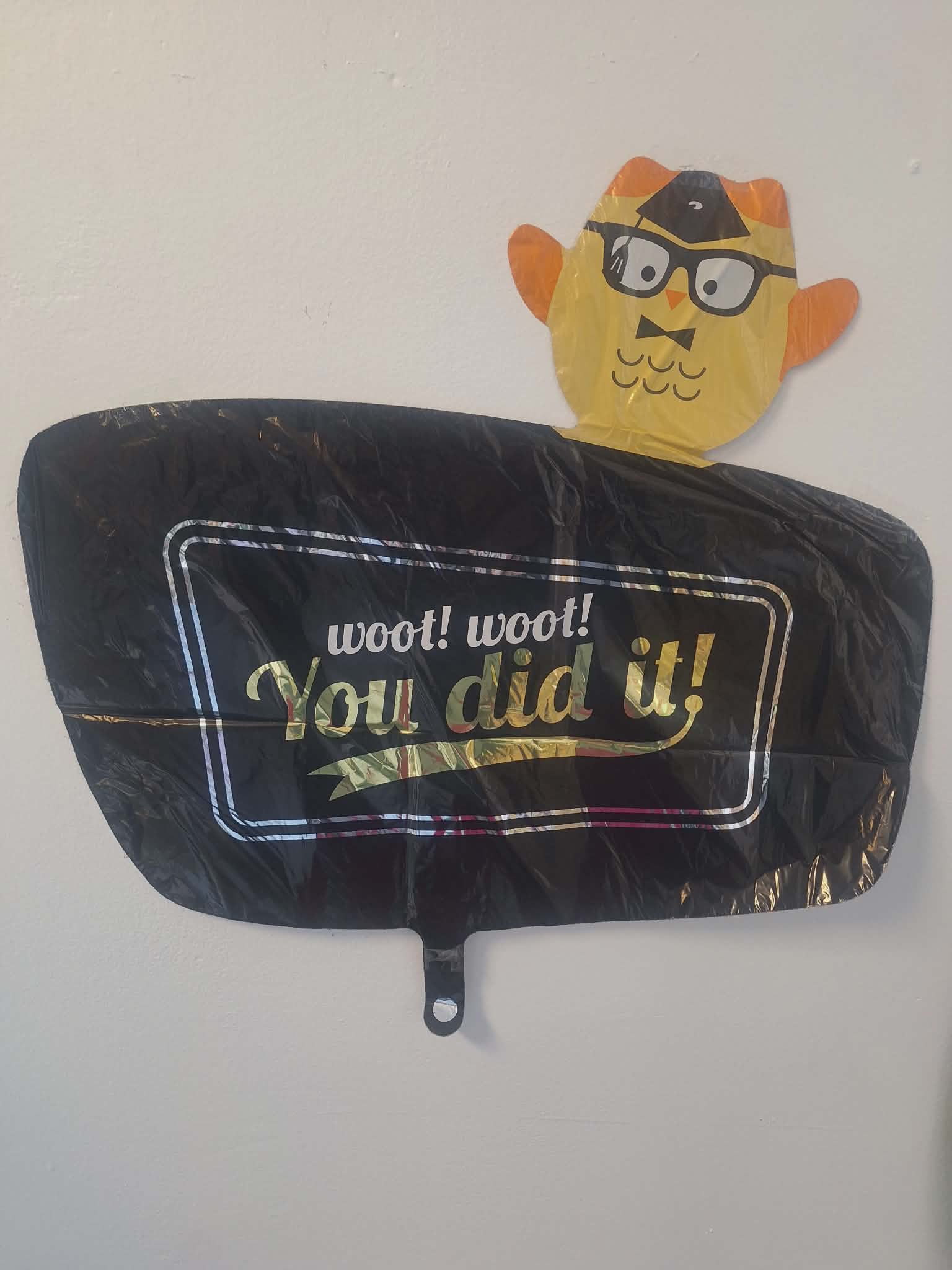 Black congratulatory balloon with a cartoon owl topper