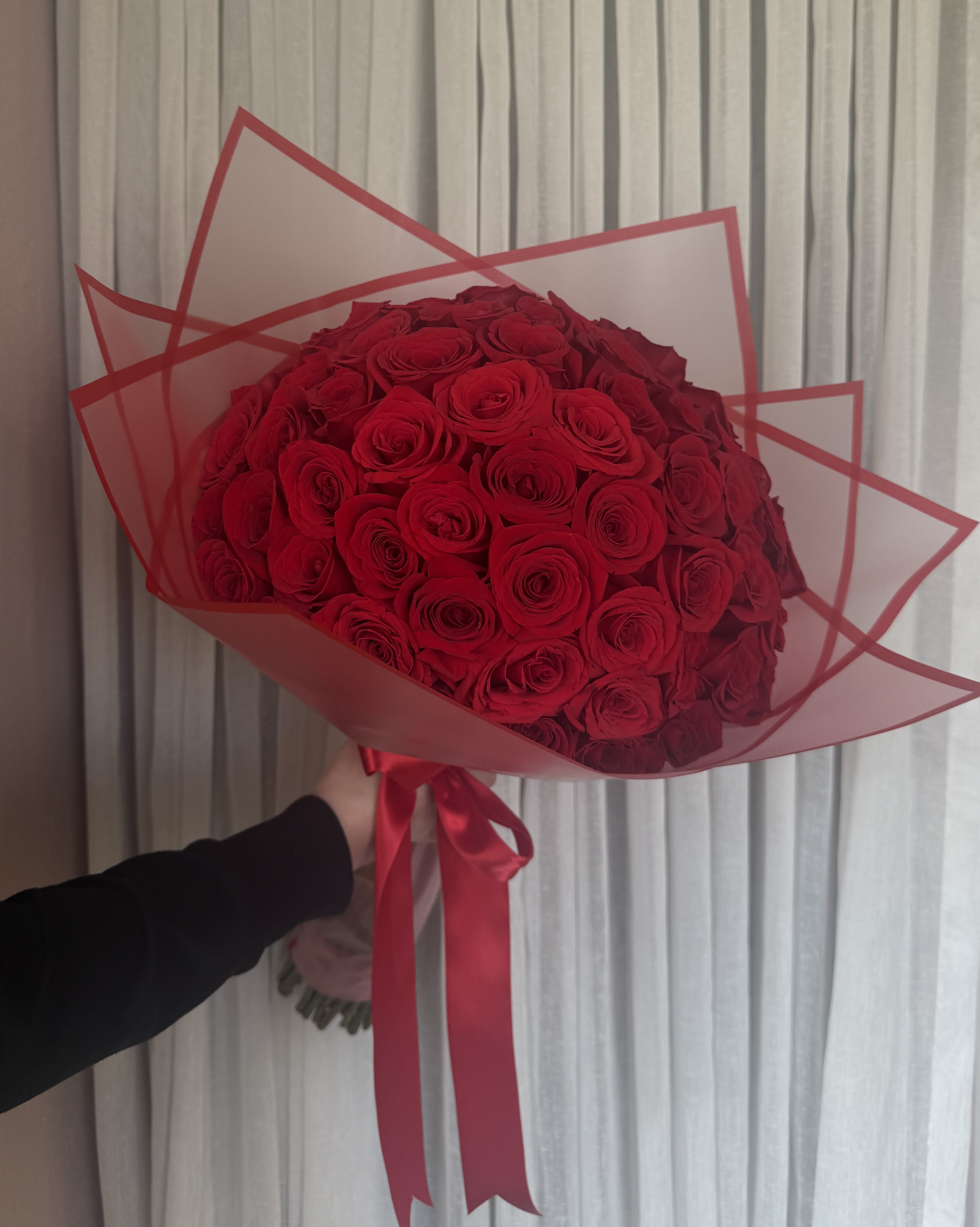 Large bouquet of red roses wrapped in red-edged paper