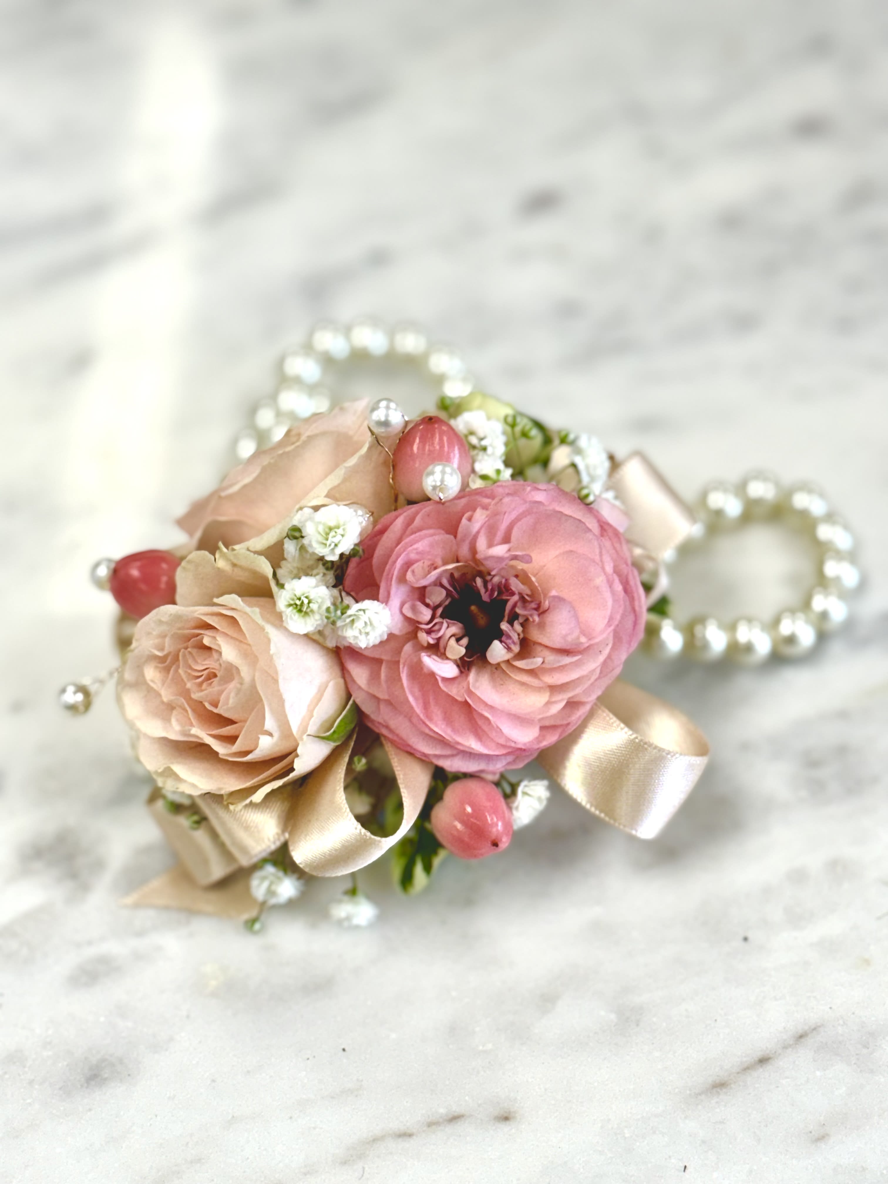 Small pink and blush floral corsage with ribbon and pearl accents