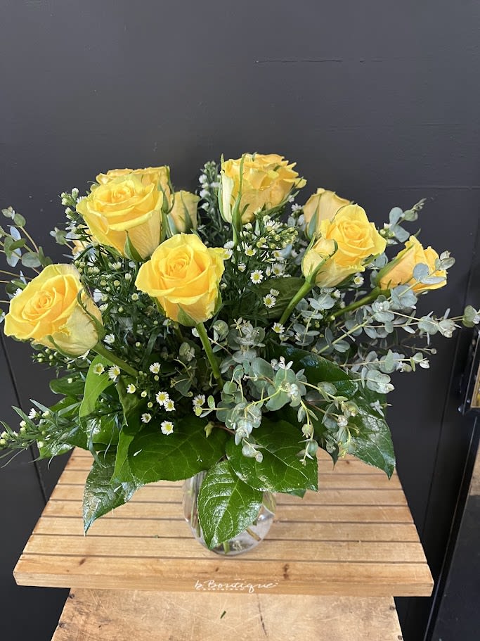 Yellow roses arranged in a clear glass vase with small white filler flowers