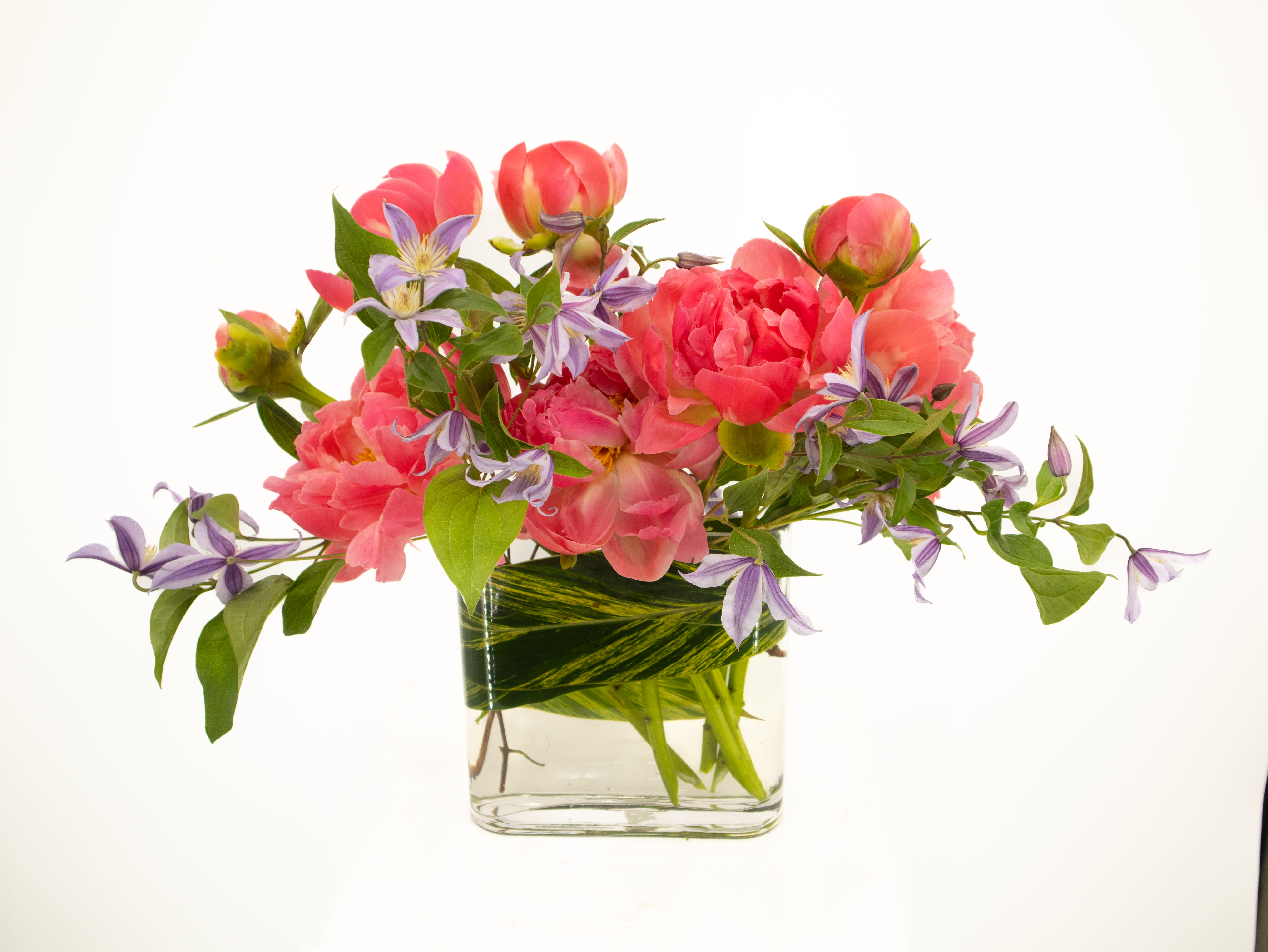 Pink flowers and purple blossoms arranged in a clear glass vase