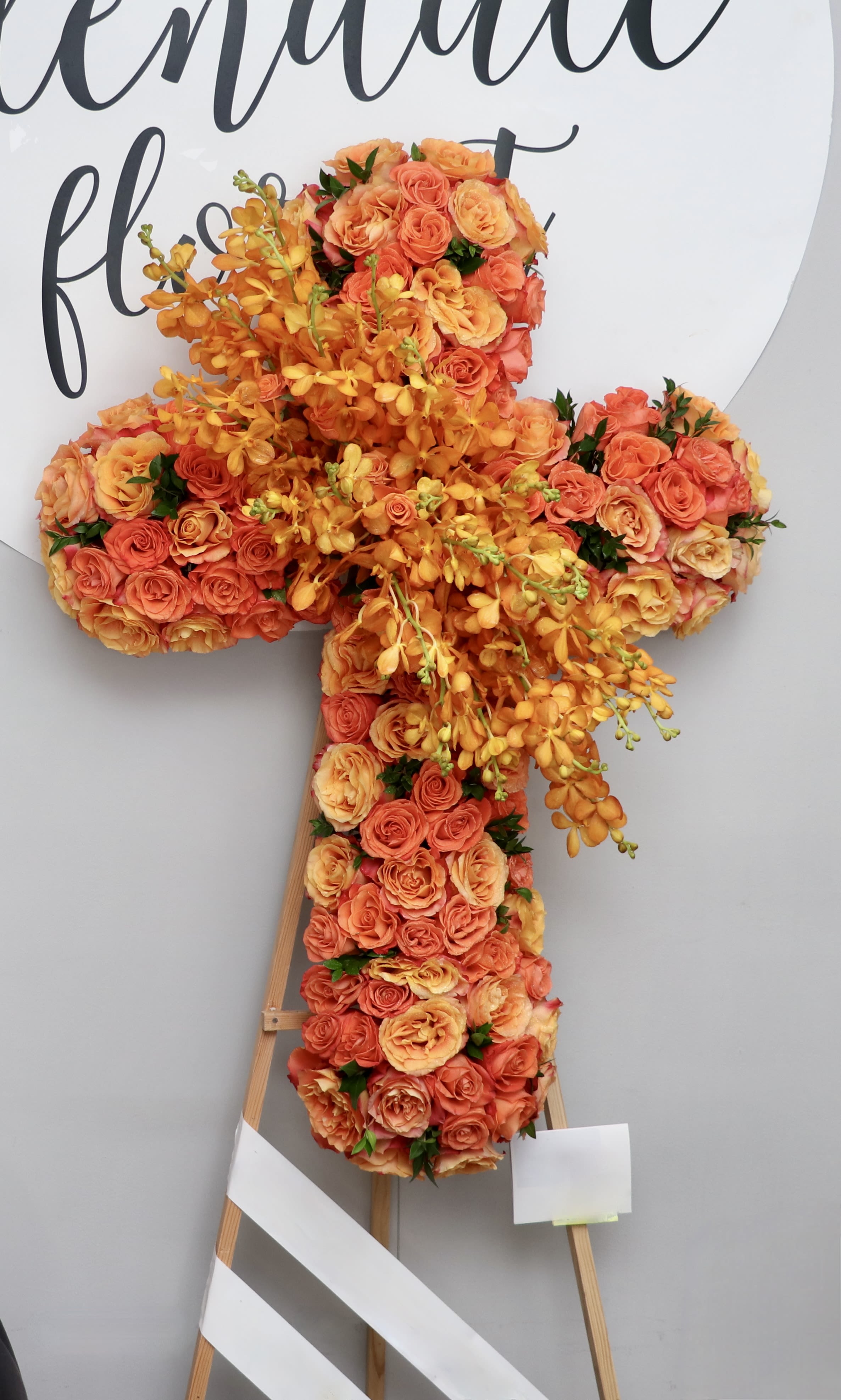 Orange Roses and Orchids Cross  - This cross is covered in orange roses and orchids.    We include easel, printed banner and delivery (some fees may apply). An additional banner can be added for $15.    Standard size is 30'', deluxe is 36'', and premium is 42''.