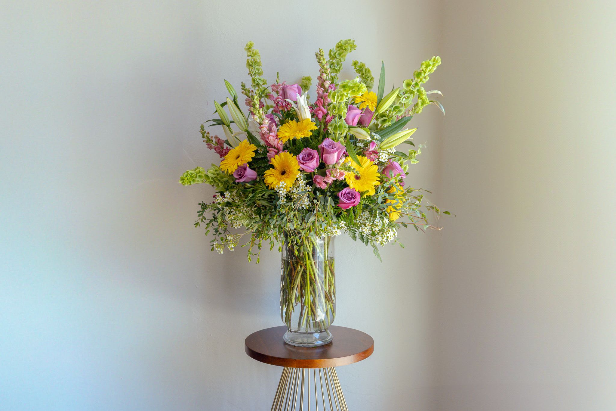 Mixed bouquet of pink and yellow flowers in a clear glass vase