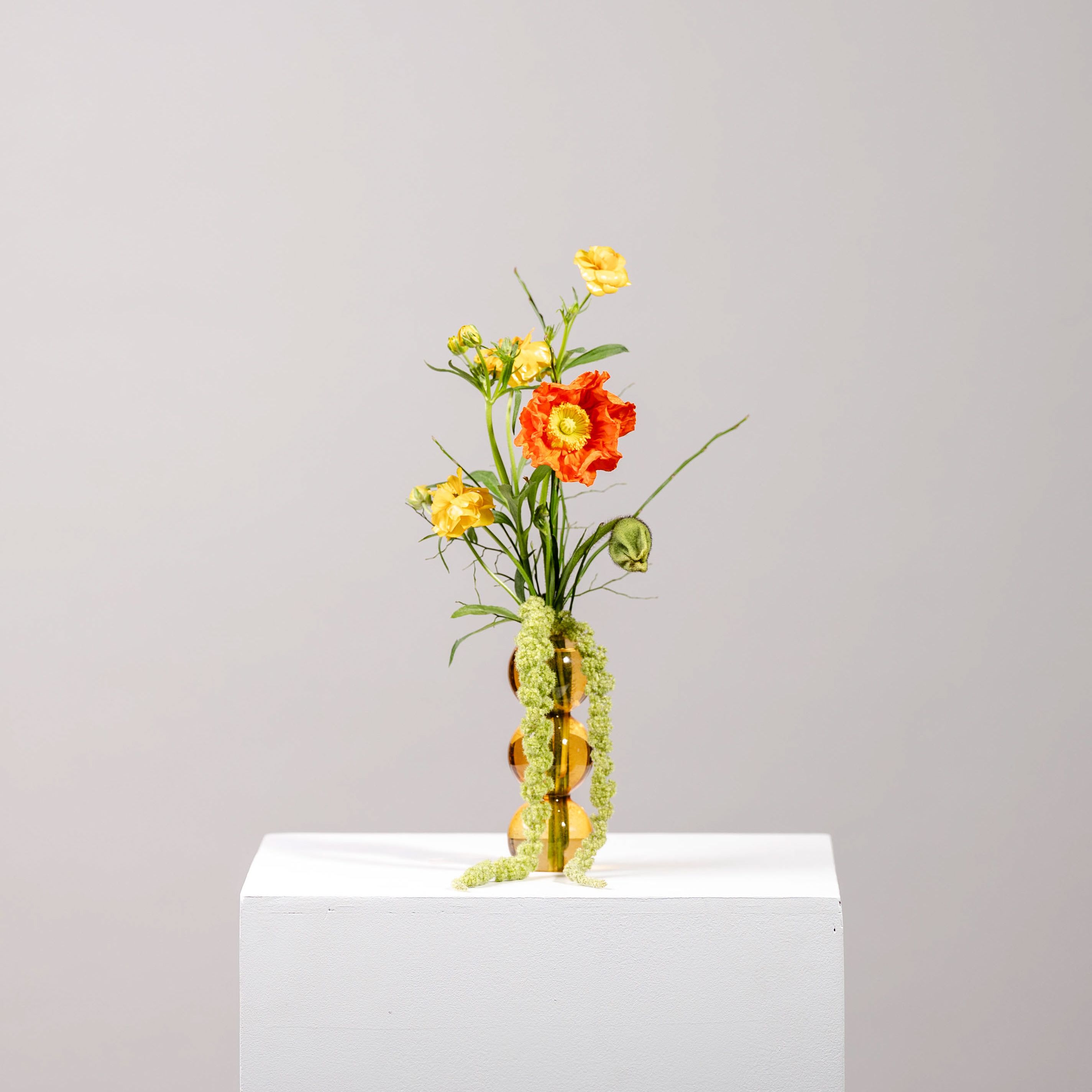 Small orange and yellow flower arrangement in an amber vase