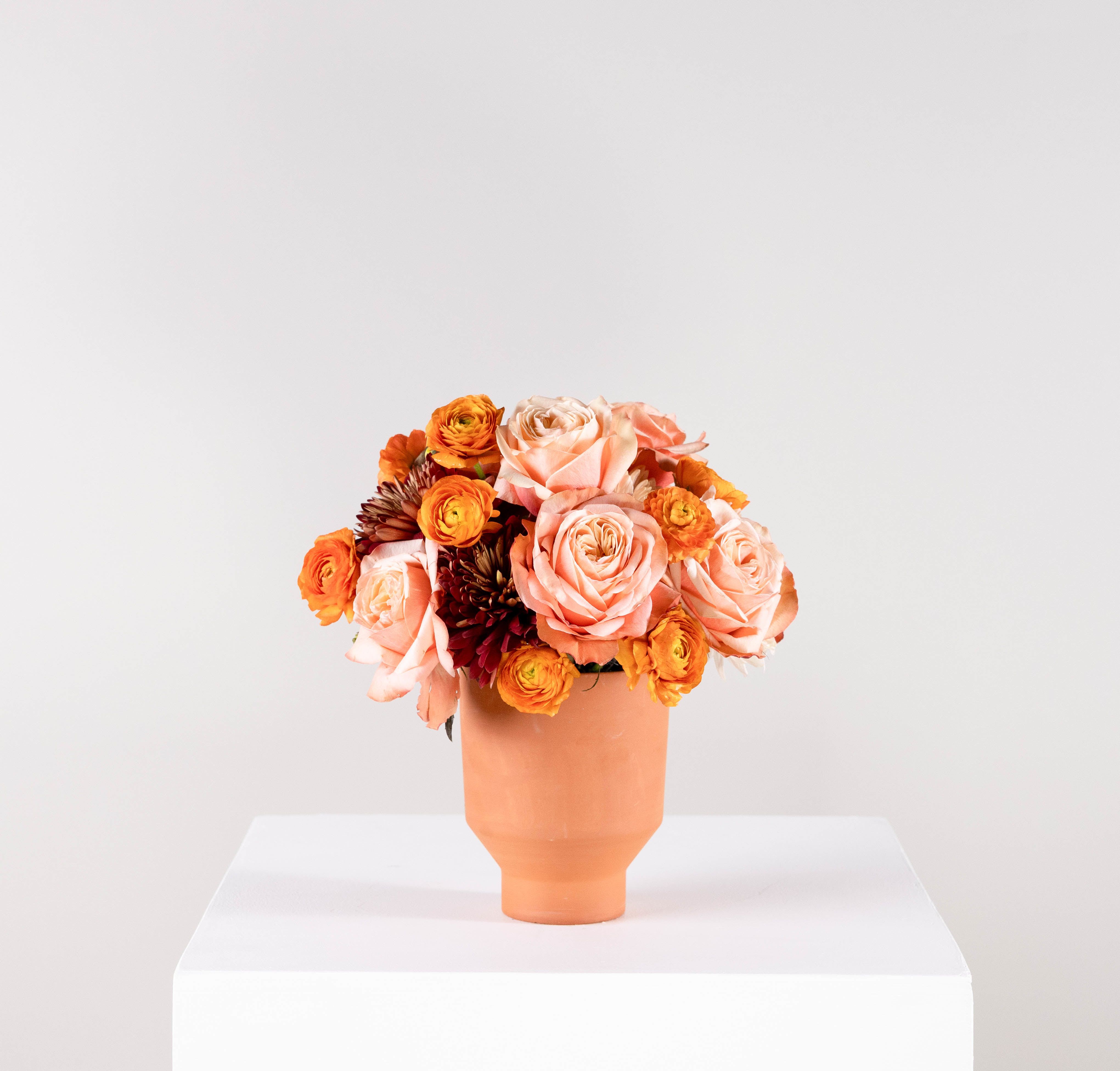 Peach and orange rose bouquet in a terracotta vase