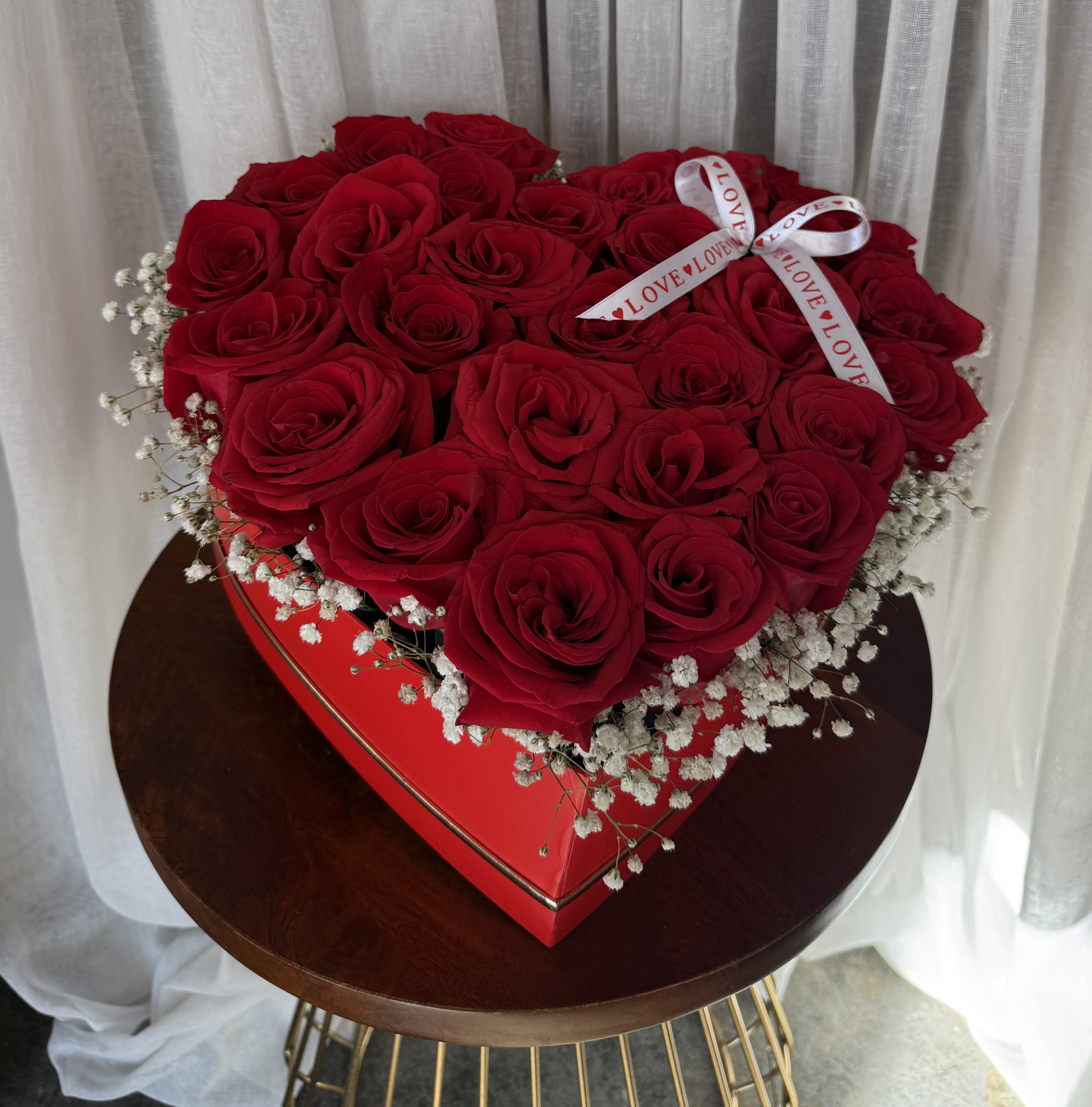 Heart-shaped box filled with red roses and baby's breath