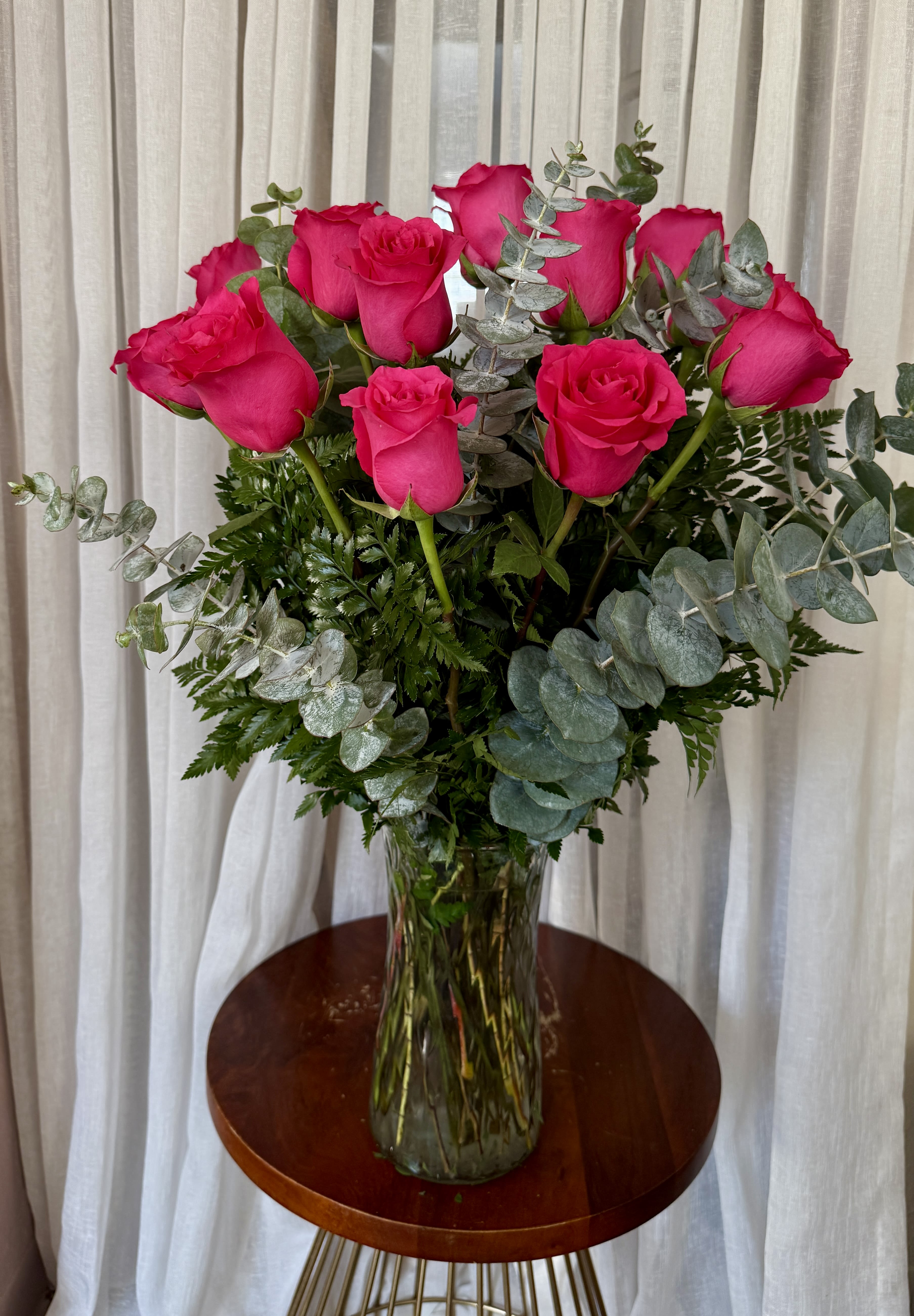Hot pink roses in a clear glass vase with eucalyptus