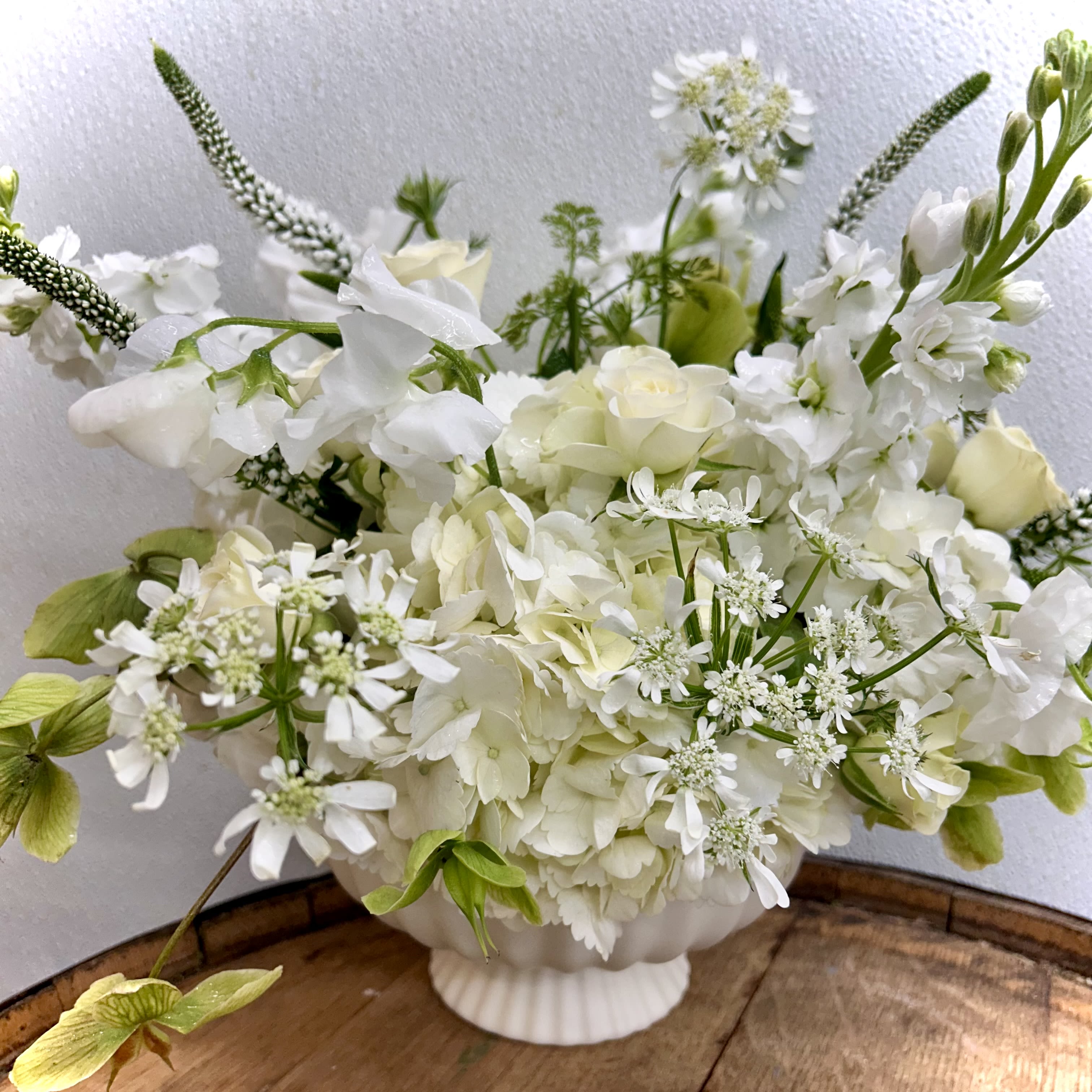 Sonata Blanca - A soft, elegant arrangement that reads as peaceful and refined, Sonata Blanca is a white floral centerpiece ideal for any occasion where understated beauty matters. The compact cluster of white hydrangea blooms and the freshest hand selected florals creates a stunning understated presentation.  