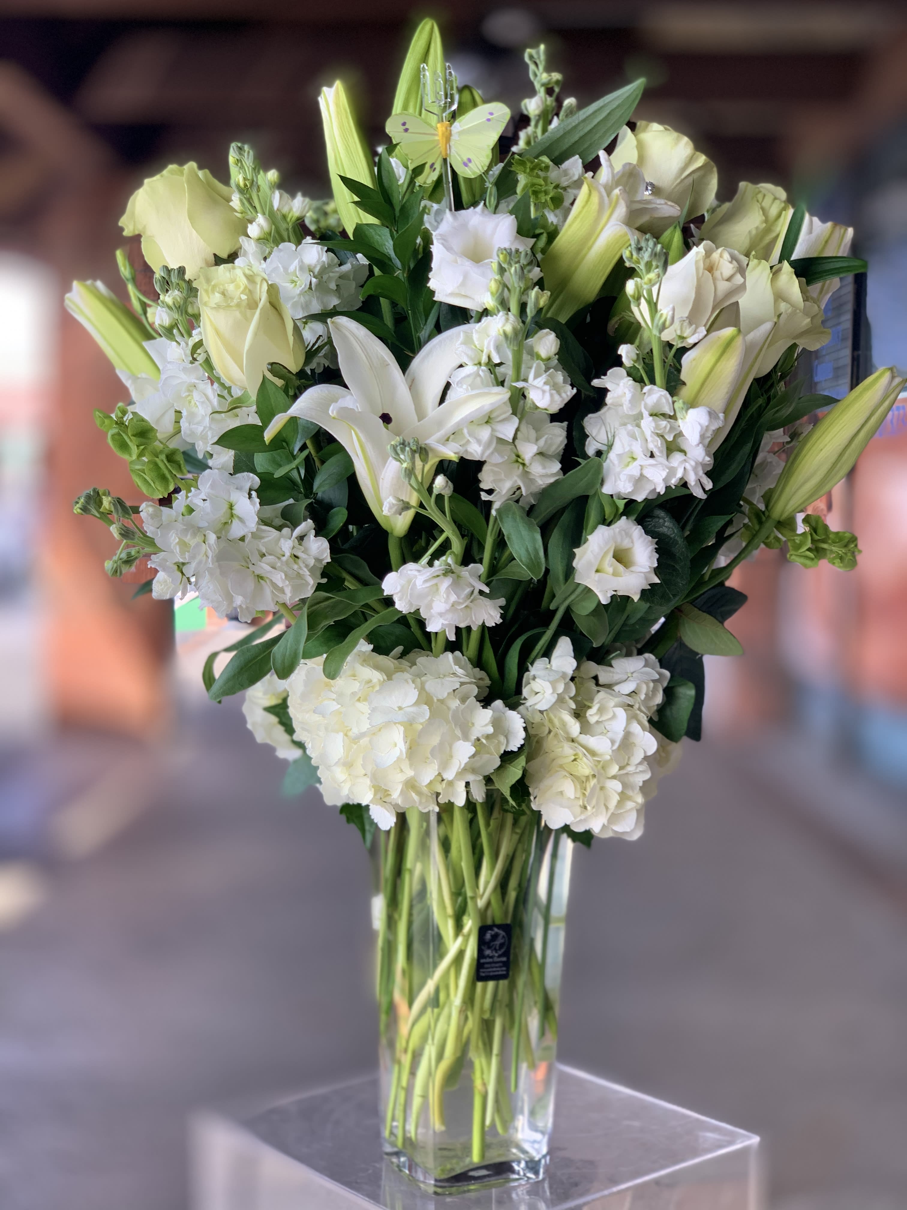 White lilies and pale roses in a tall glass vase