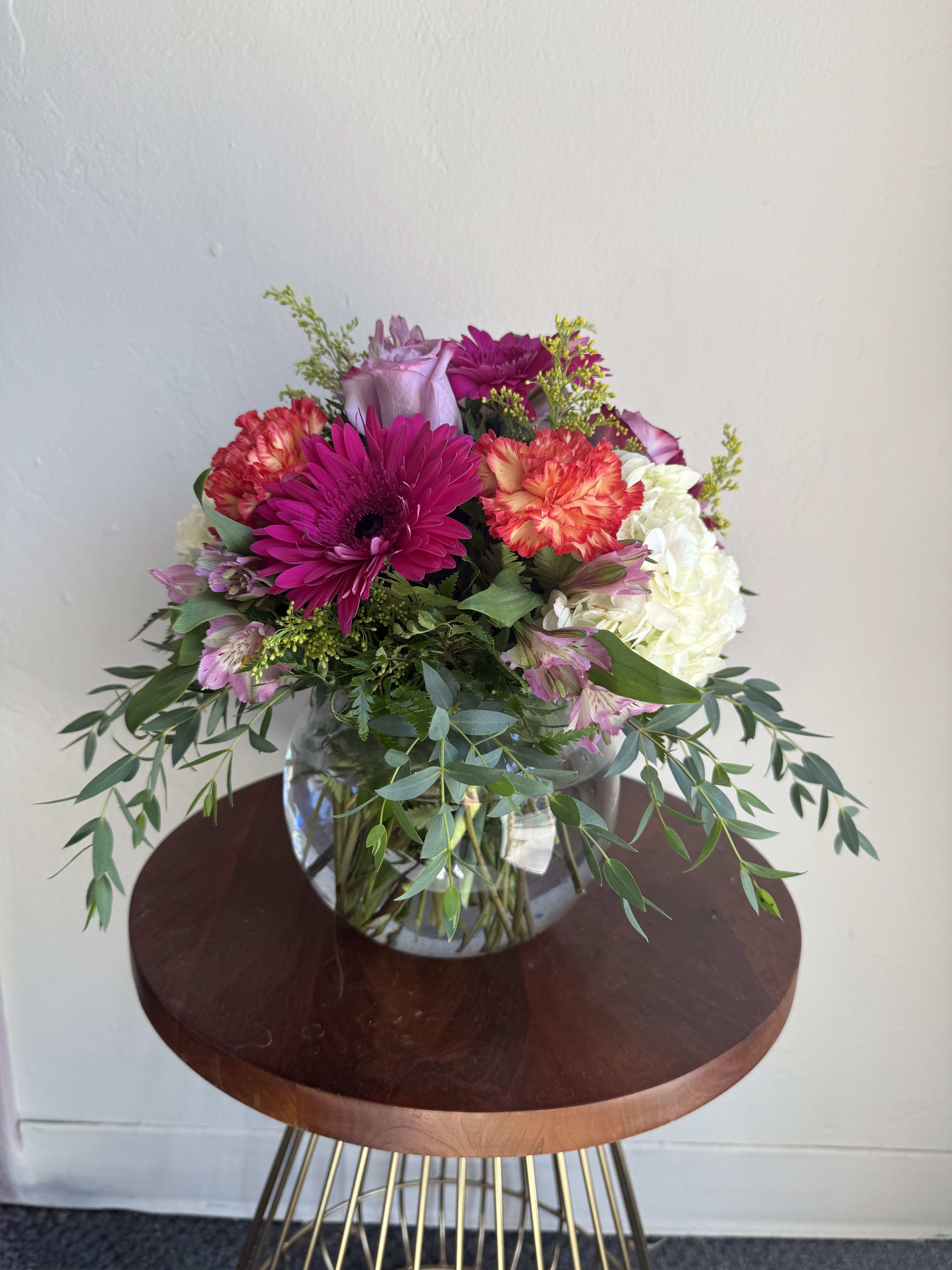Mixed bouquet of pink, white, and coral flowers in a glass vase