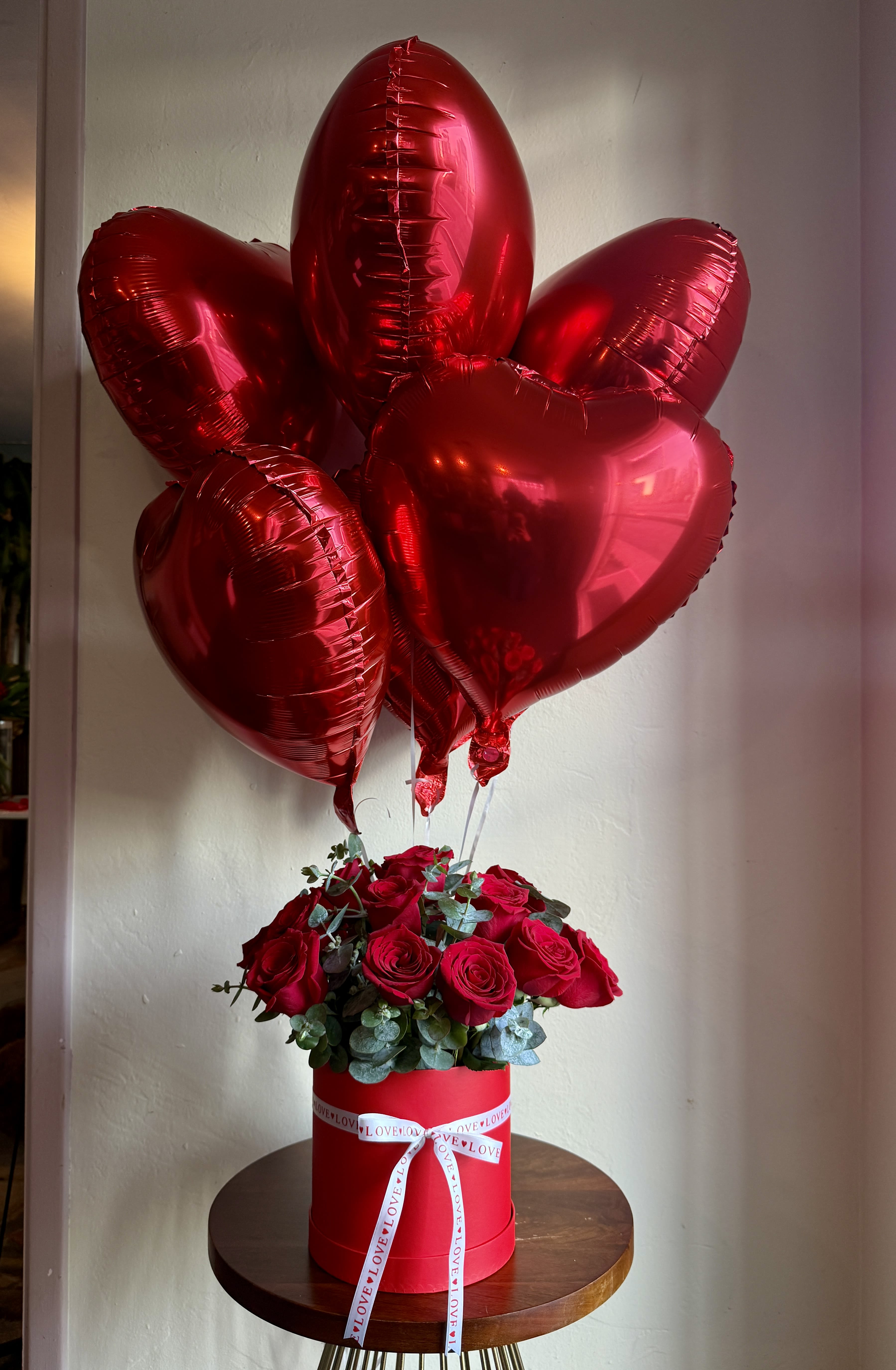 Red roses in a round box with red heart balloons above