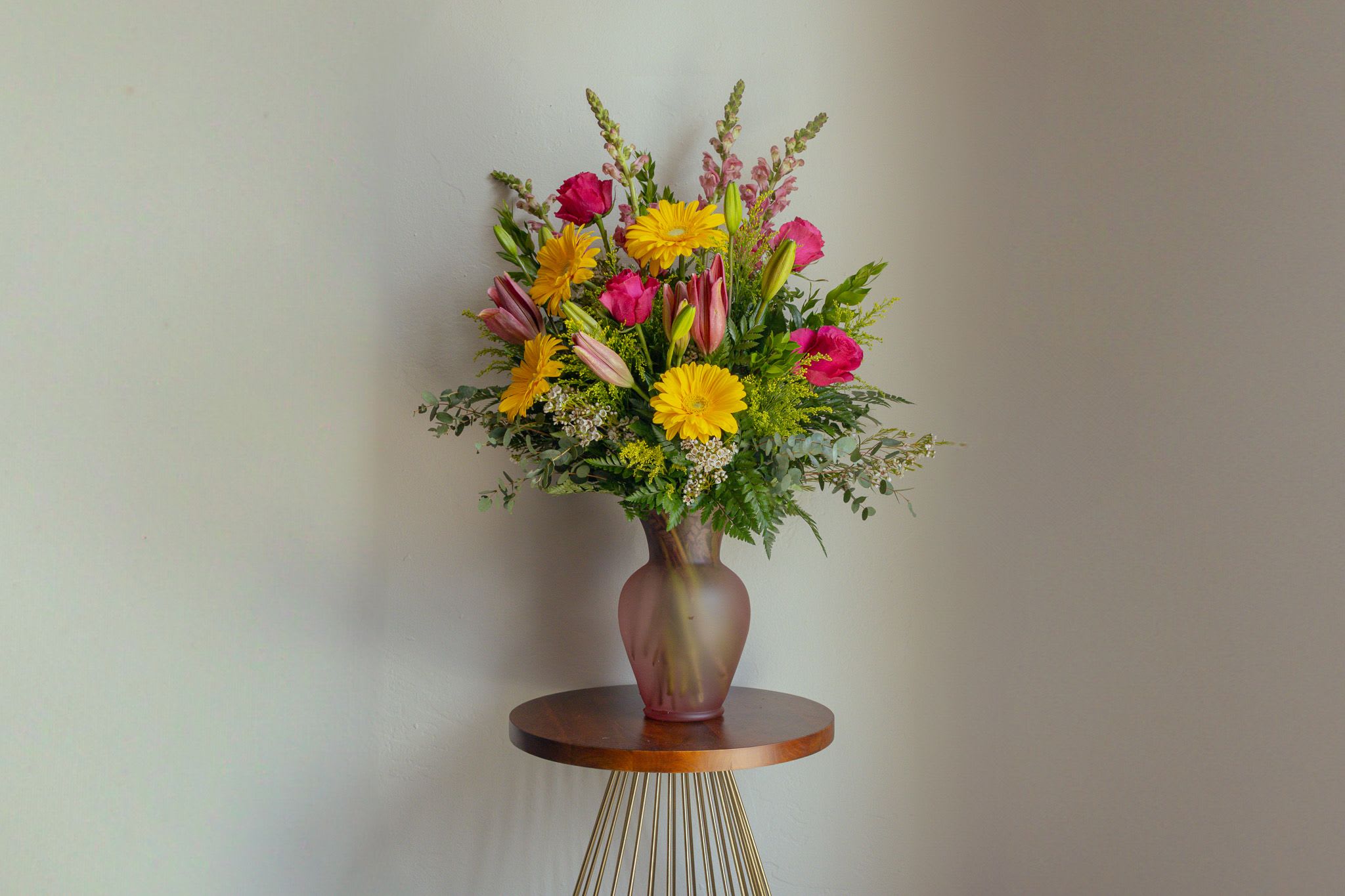 Mixed bouquet of yellow daisies, pink lilies, and magenta blooms in a vase