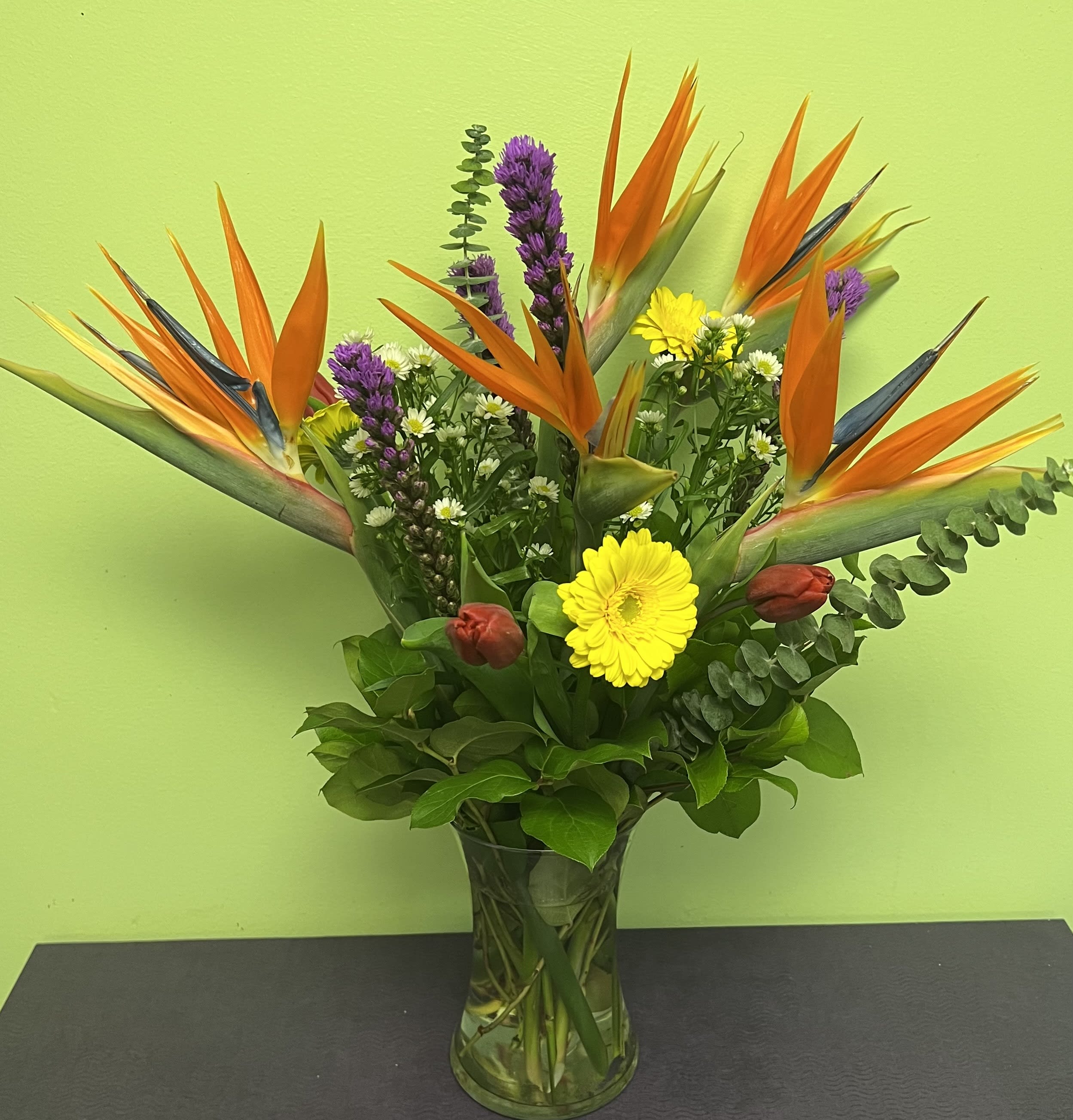Bouquet of orange bird of paradise and mixed flowers in a glass vase
