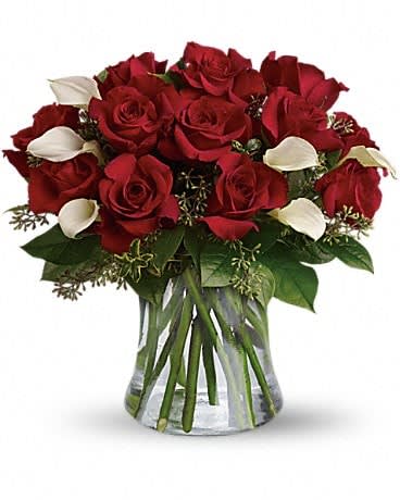 Bouquet of red roses and white calla lilies in a clear glass vase