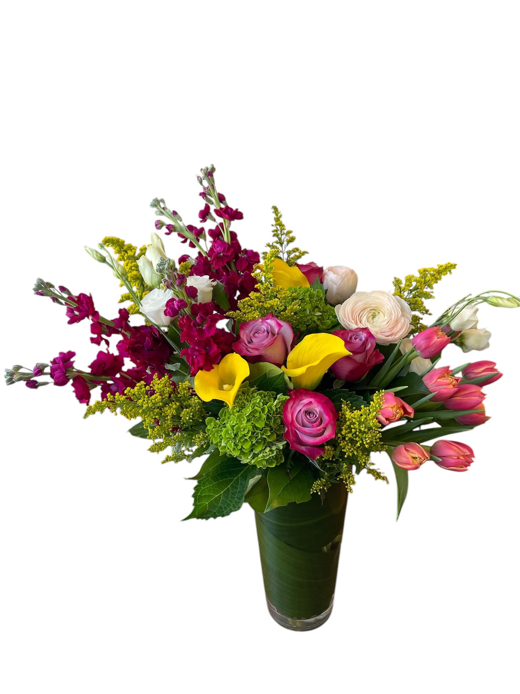 Mixed bouquet with pink roses, yellow calla lilies, and magenta flowers in a glass vase