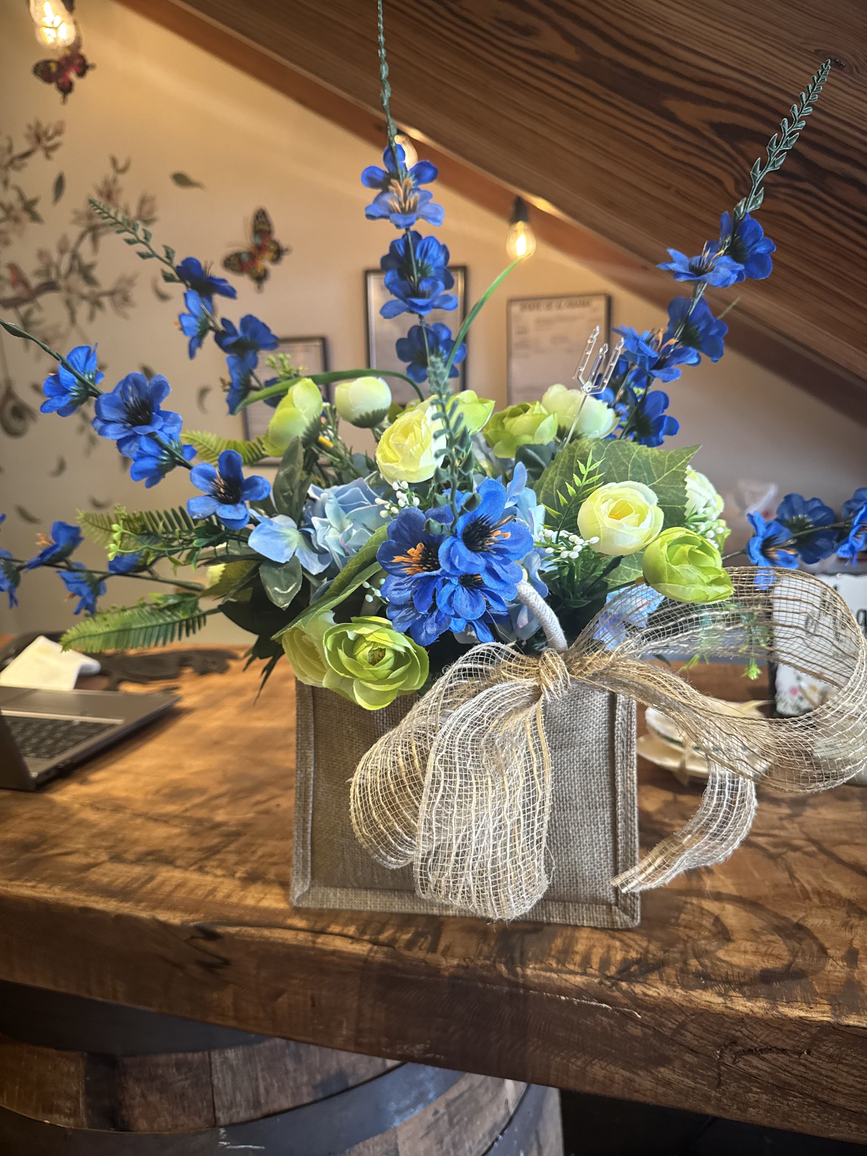 Blue and lime floral arrangement in a burlap box with a sheer bow