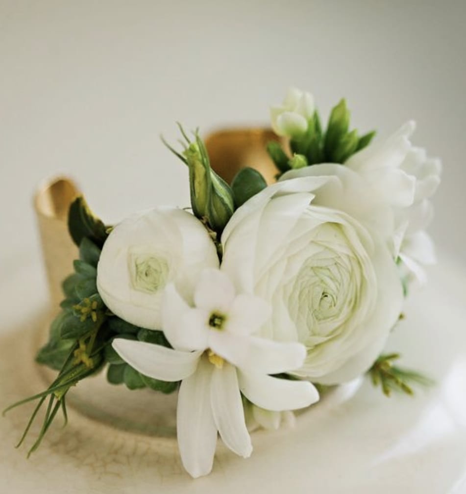White ranunculus and small white blossoms arranged in a compact bouquet
