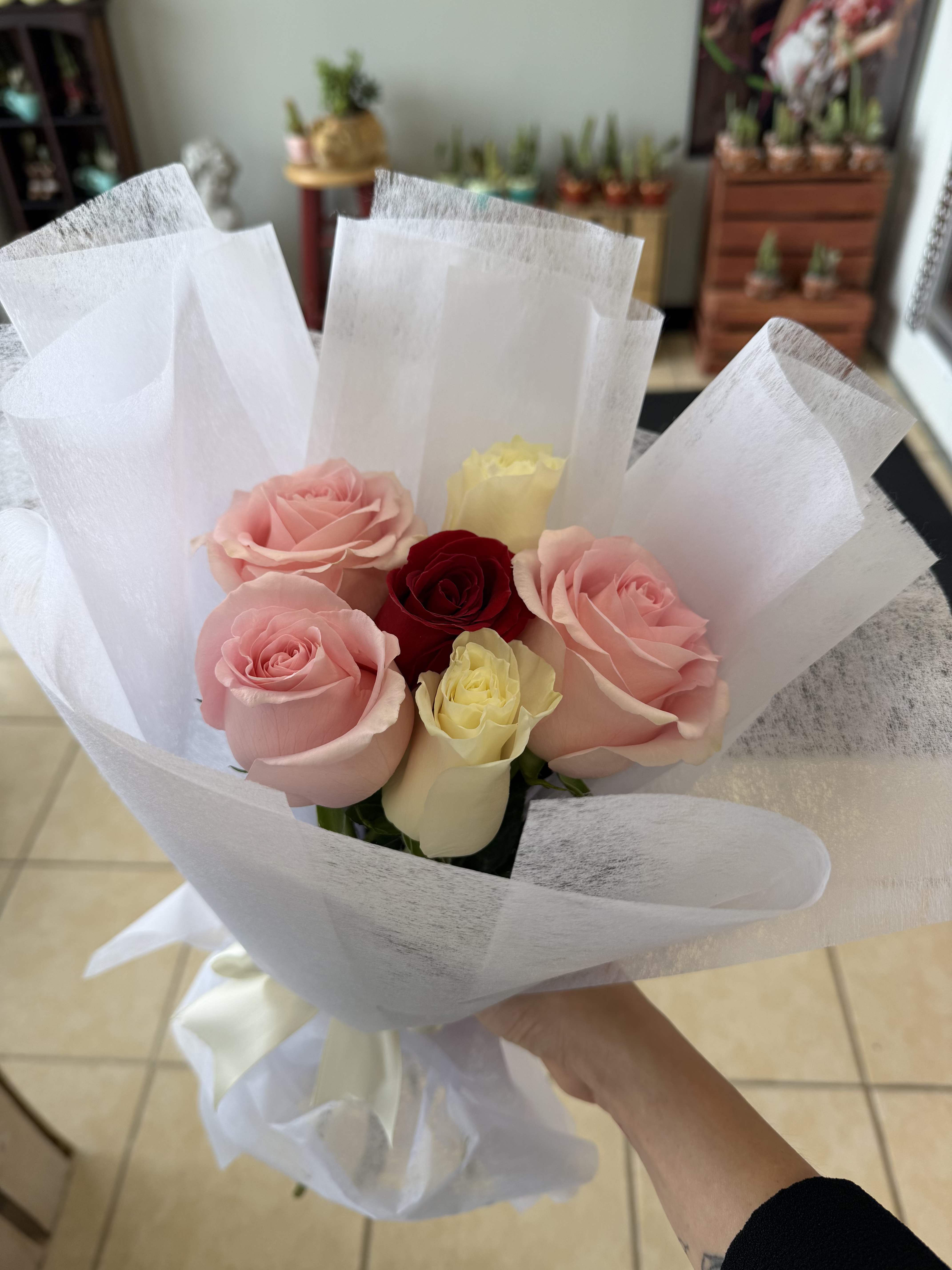 cutie bouquet - A rounded hand-tied rose bouquet that reads like a sweet kiss-perfect as a birthday bouquet or anniversary roses to celebrate love and affection. The "cutie bouquet" pairs soft pink, deep red, cream-white, and a hint of sunny yellow to create a romantic yet cheerful arrangement that makes the person you're thinking of feel truly seen and celebrated.  This arrangement features tightly clustered roses in blush pink, deep red, pale cream, and subtle yellow tones, wrapped in crisp white paper and finished with a neat ribbon for a clean, airy presentation. The compact, rounded shape keeps the focus on the lush rose heads and their velvety texture; the white wrap brightens the palette so the colors pop whether on a mantel or bedside table.  Send this as an anniversary surprise, a birthday treat, or a "just because" gift that says affection and joy. Hand-tied for easy display, the bouquet arrives ready to place in a vase-trim stems and change the water every other day to help the roses last longer.