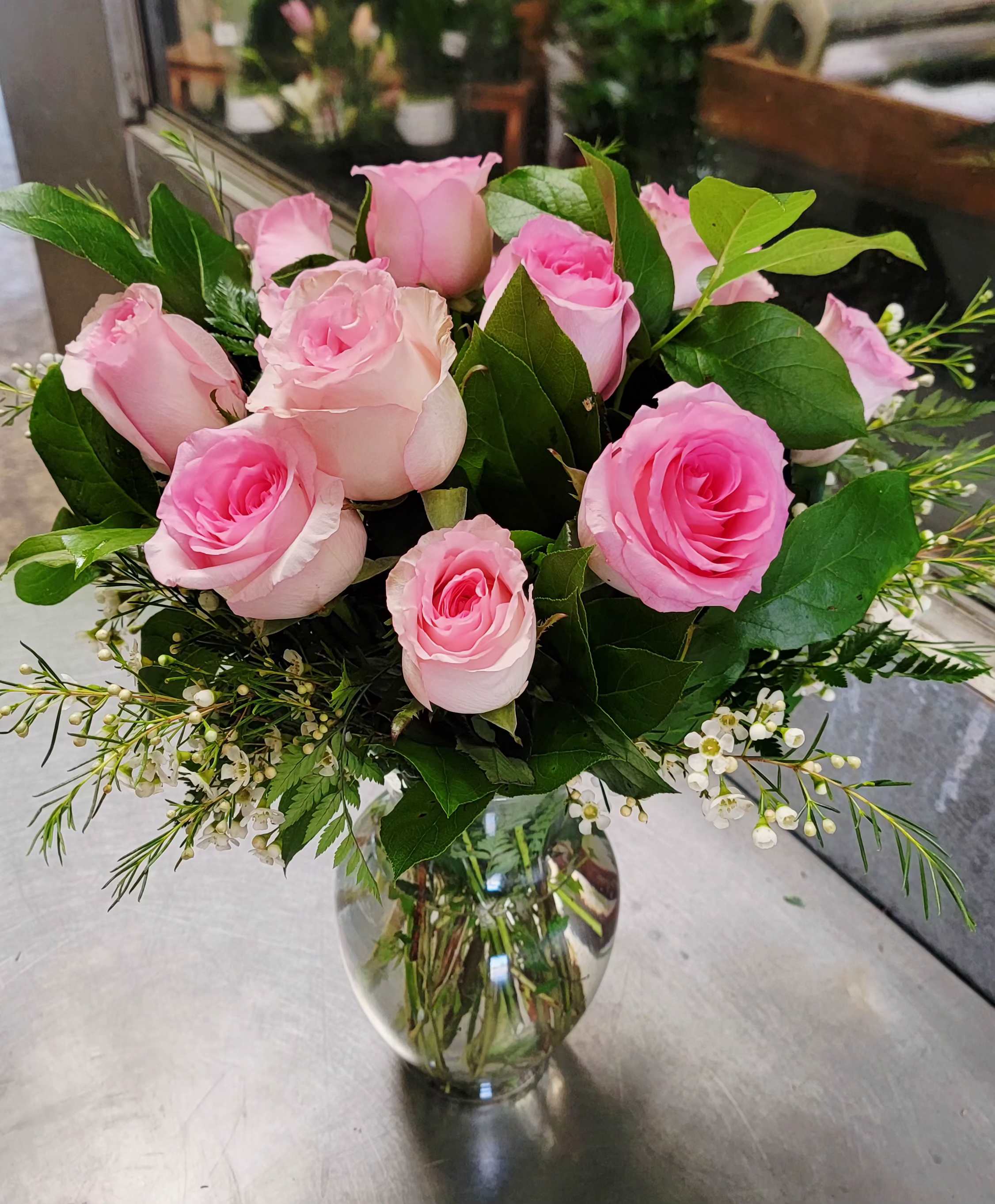 Pink roses arranged in a clear glass vase with small white filler flowers