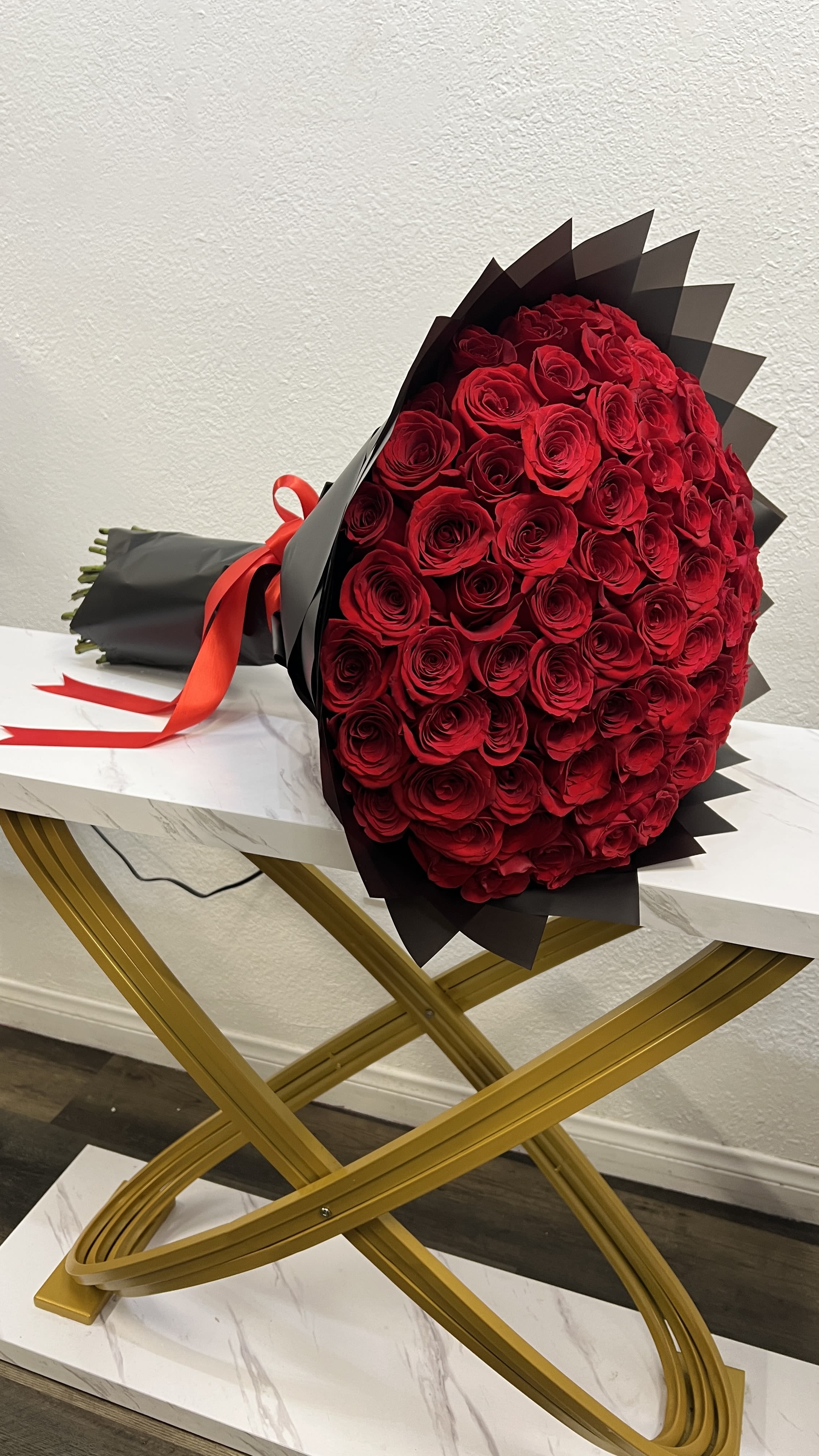 Large bouquet of red roses wrapped in black paper with a red ribbon
