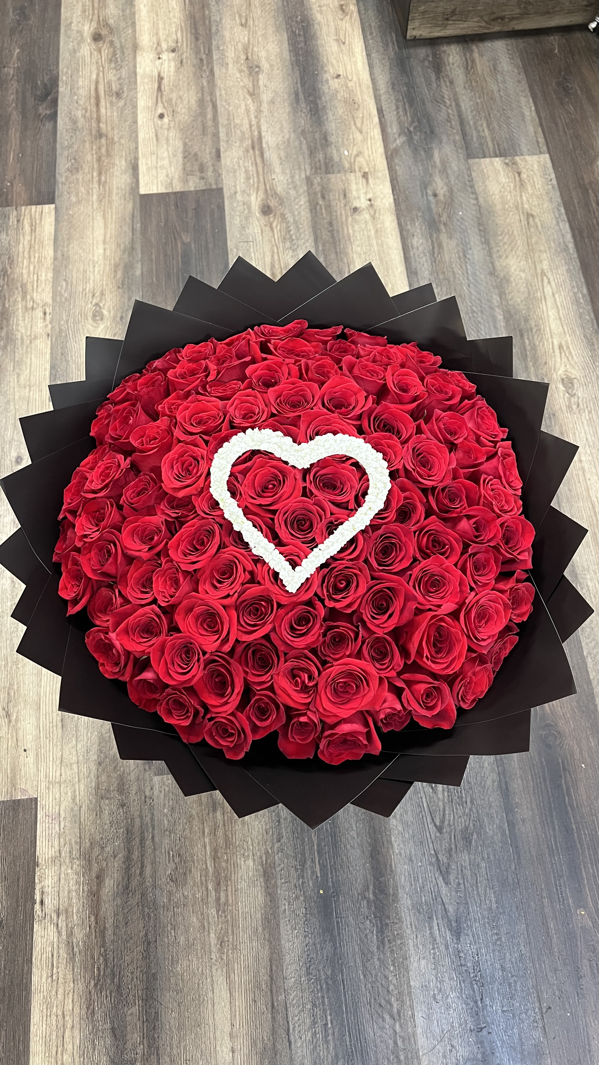 Round bouquet of red roses with a white heart accent
