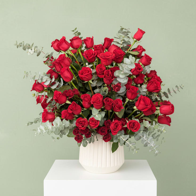 Centennial Romance - An unforgettable expression of love and grandeur, Centennial Romance features 100 premium long-stem red roses artfully designed with delicate spray roses and fresh eucalyptus for added texture and movement. Overflowing with richness and depth, this show-stopping arrangement is crafted in a modern ceramic vase, creating a perfect balance of elegance and drama. Whether for a milestone celebration or a truly meaningful gesture, this piece is designed to leave a lasting impression.