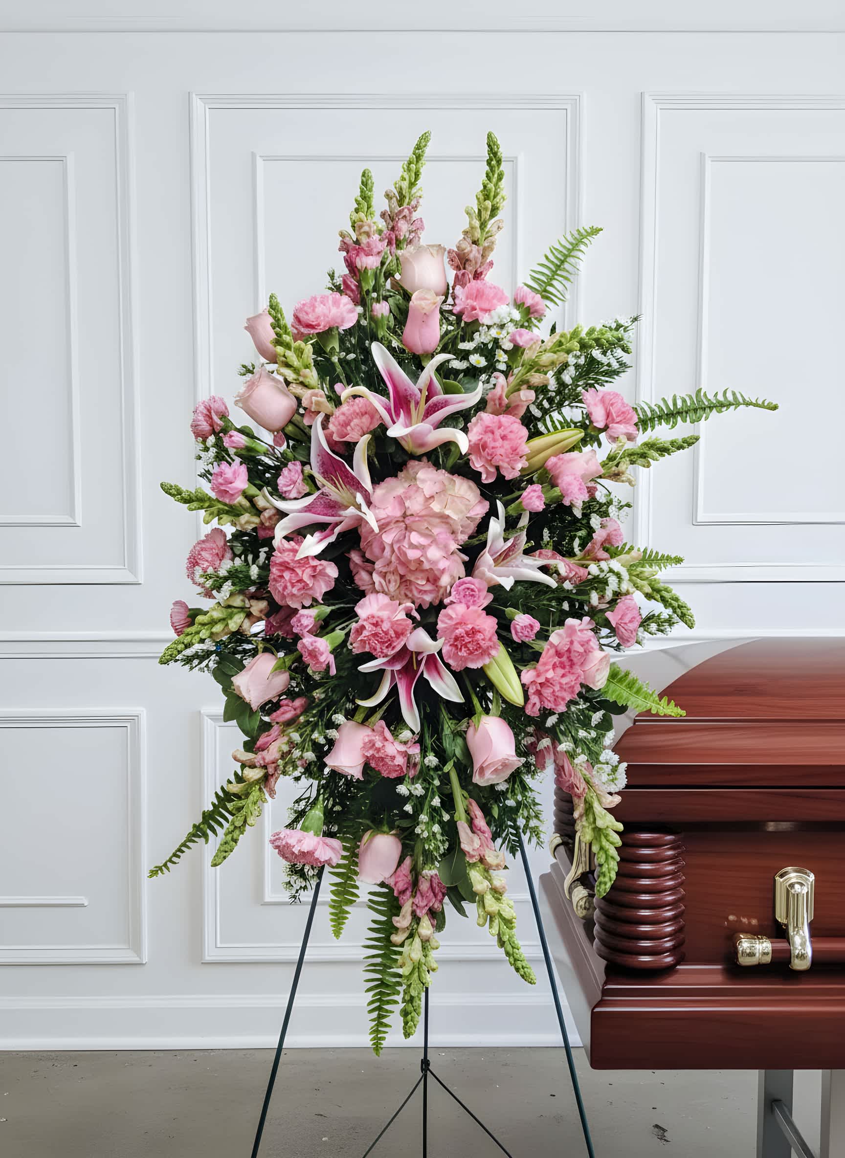 Sweet Remembrance - A graceful and heartfelt tribute, this elegant standing spray is designed in soft shades of pink to convey love, compassion, and remembrance. Featuring a delicate blend of roses, lilies, hydrangeas, and seasonal blooms, each flower is thoughtfully arranged to create a sense of peace and gentle beauty.  With its flowing design and lush greenery, this piece offers a comforting presence, honoring a life with warmth and sincerity while bringing light to those who gather in remembrance.  Available in multiple sizes to suit your needs, this arrangement serves as a timeless expression of love and heartfelt sympathy.