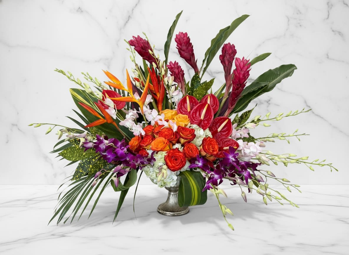 Tropical Sunset Luxe - A bold and vibrant tribute, this stunning tropical arrangement is designed to celebrate a life full of energy, warmth, and unforgettable moments. Featuring an eye-catching blend of birds of paradise, anthuriums, orchids, and roses, this piece radiates color and personality in every direction.  Lush greenery and exotic textures create a striking, modern silhouette, making this arrangement a beautiful choice for honoring someone who lived life with passion and spirit. Its dynamic design brings a sense of strength, beauty, and remembrance to any setting.  Perfect for services or memorial gatherings, this arrangement offers a unique and uplifting expression of love, respect, and lasting admiration.