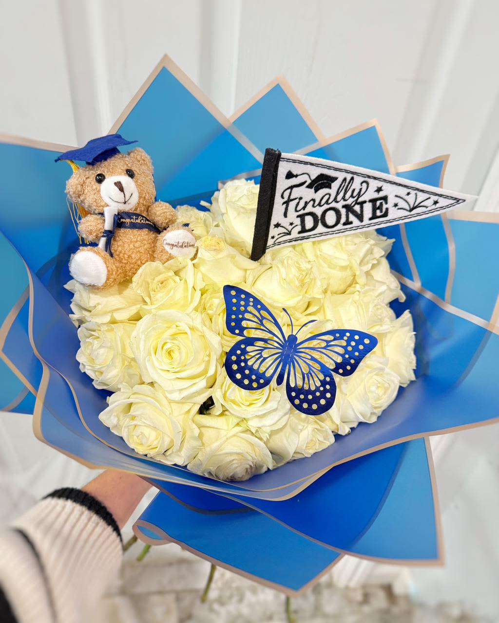 Bouquet of white roses with a teddy bear and graduation decorations