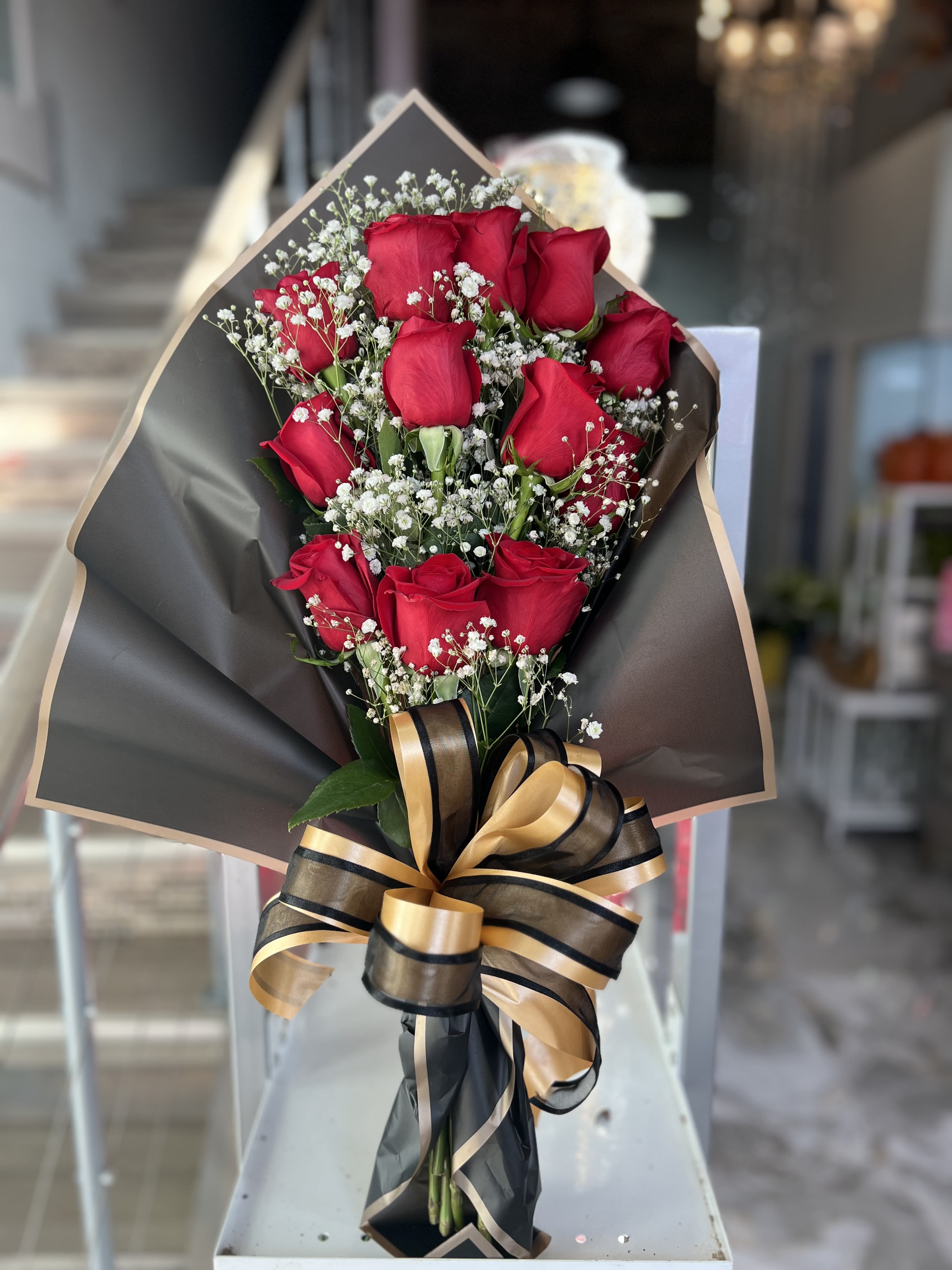 Bouquet of red roses with baby's breath and a black-and-gold ribbon