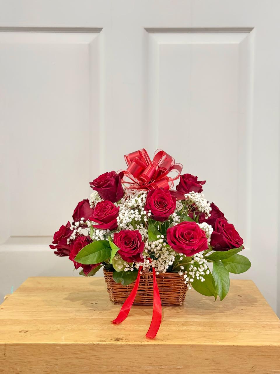 Basket of red roses with baby's breath and a red ribbon bow