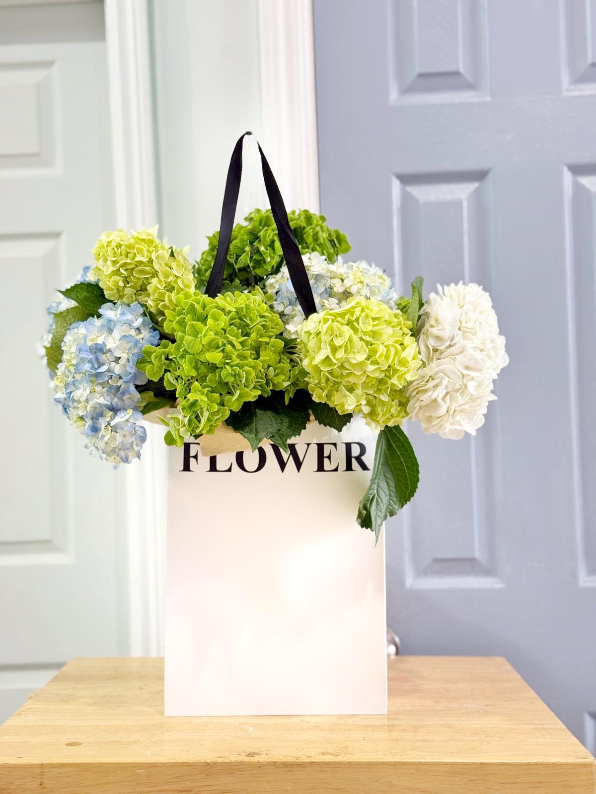 Hydrangea blooms in a white gift bag with black handles