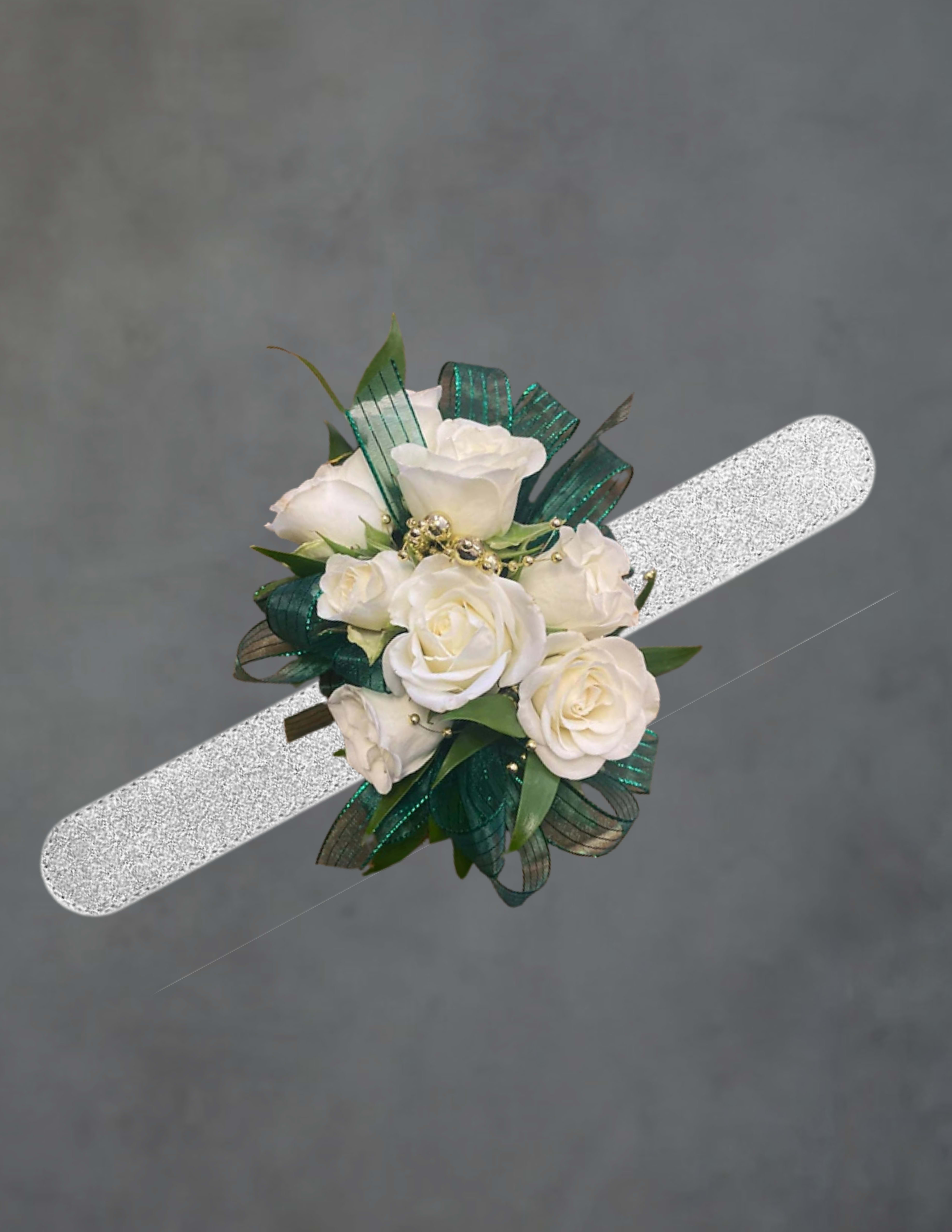 Green and white corsage - Silver wristband-worn white rose corsage perfect for prom, wedding, or any dressy occasion where a refined touch is needed. The clustered white roses sit compactly on a silver wristband so the person you're gifting will feel elegantly polished and comfortable all evening - a subtle statement that reads formal and celebratory without overpowering their look.  Teal-green ribbon loops and small gold bead accents weave among the blooms, adding cool green contrast and a hint of sparkle to the predominantly white palette. The design is compact and delicate rather than large or dramatic, finished with decorative ribbon for texture and secure wear on the wrist.  Ideal for bridesmaids, prom dates, or anyone you want to mark with a thoughtful, wearable floral touch; it makes the recipient feel noticed and gracefully dressed for the moment. Because of its close-clustered style, handle gently and store flat in a cool place before the event to keep the roses looking fresh.
