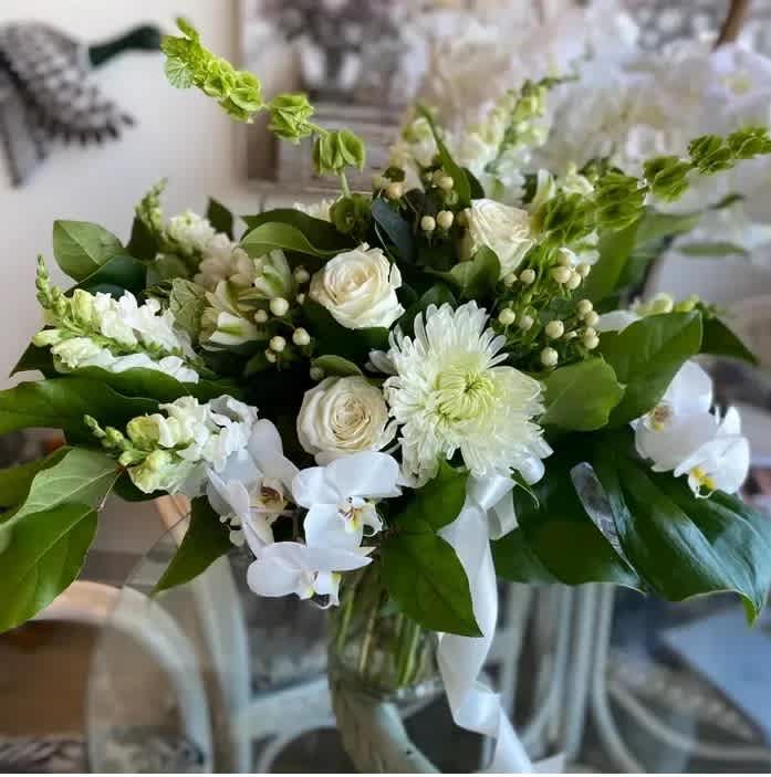 White floral bouquet with roses, orchids, and chrysanthemums in a glass vase