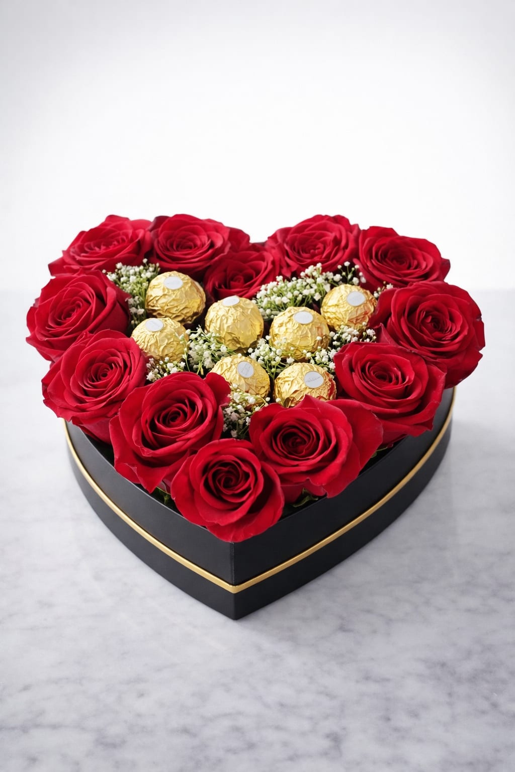 Romantic lux rose box - A stunning heart-shaped arrangement featuring premium red roses paired with Ferrero Rocher chocolates and delicate baby’s breath, elegantly presented in a black and gold box. Perfect for romantic occasions, anniversaries, or luxury gifting.