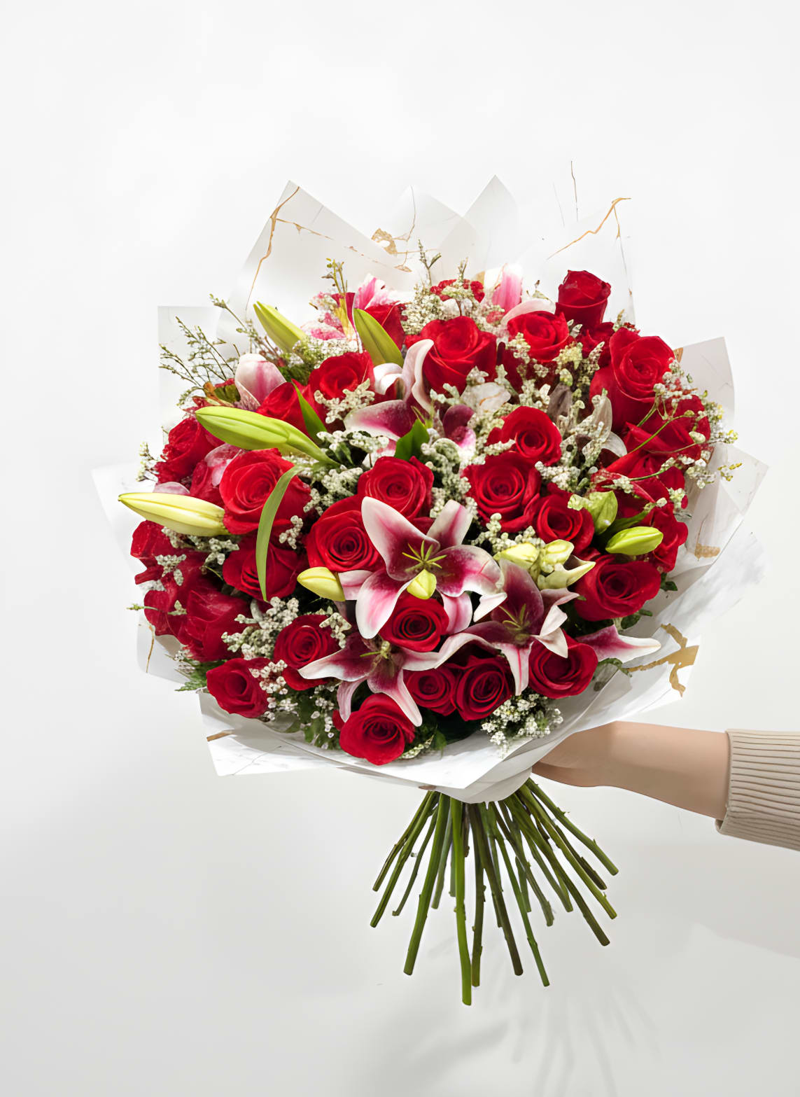 Bouquet of red roses and pink lilies wrapped in white paper