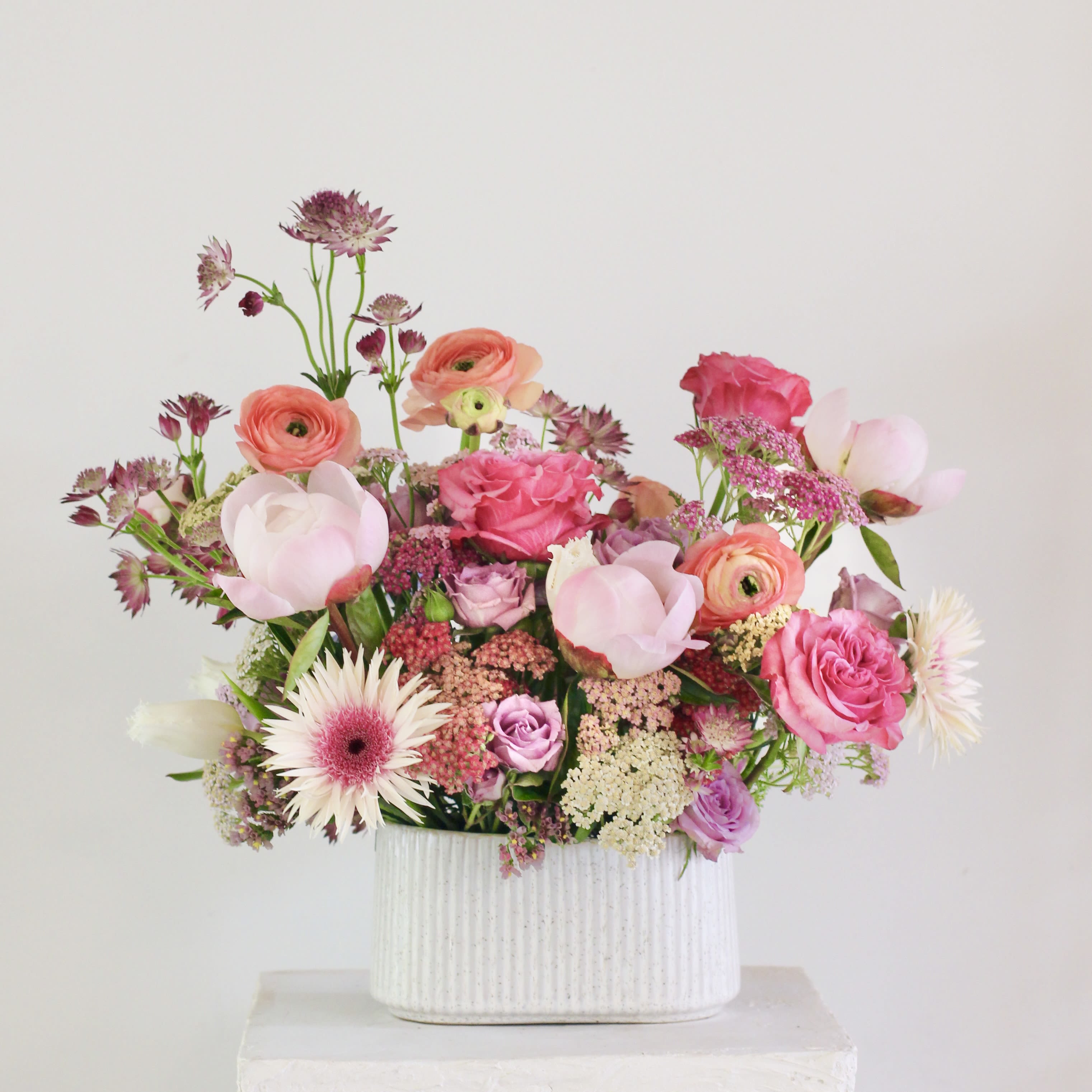 Pink and peach mixed flowers in a white ribbed vase