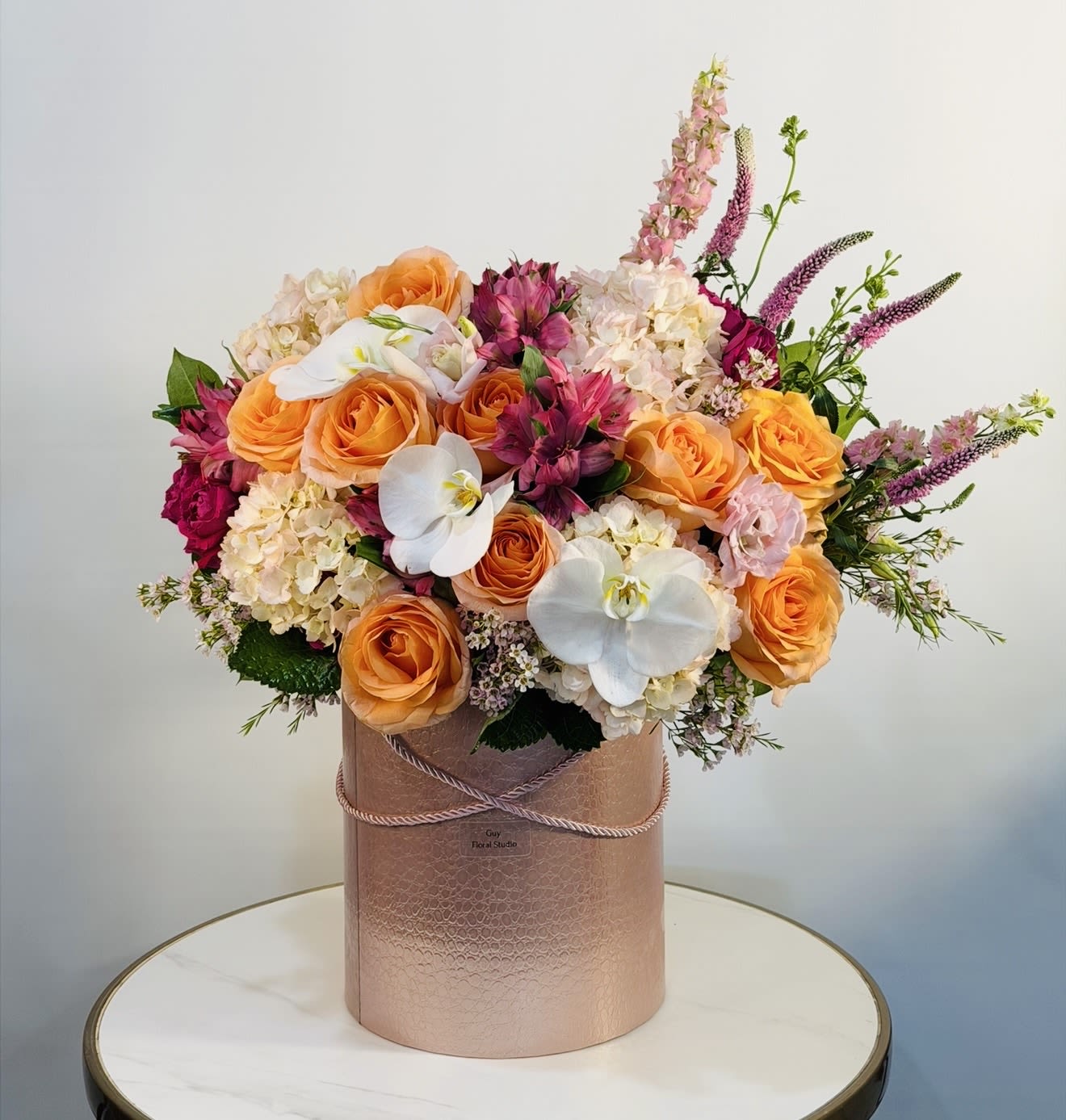 Golden Sunset Orchid Arrangement - The Golden Sunset Orchid Arrangement is a stunning luxury floral design featuring vibrant orange roses, elegant white orchids, soft hydrangeas, and seasonal blooms in warm sunset tones of pink, cream, and gold. Beautifully arranged in a premium keepsake box, the Golden Sunset Orchid Arrangement is perfect for birthdays, anniversaries, romantic gestures, or any special occasion. Its rich colors and elegant composition create a sophisticated and unforgettable gift. Each Golden Sunset Orchid Arrangement is handcrafted with fresh, high quality flowers to ensure long-lasting beauty and a luxurious presentation. We offer same day flower delivery in Los Angeles and nearby areas, including Beverly Hills, Hollywood Hills, West Hollywood, Bel-Air, Santa Monica, Culver City, Beverly Grove, and more.  Same day delivery available  Premium fresh flowers  Handcrafted luxury arrangement  Perfect for any occasion Order your Golden Sunset Orchid Arrangement today and enjoy fast, reliable same day flower delivery in Los Angeles. 