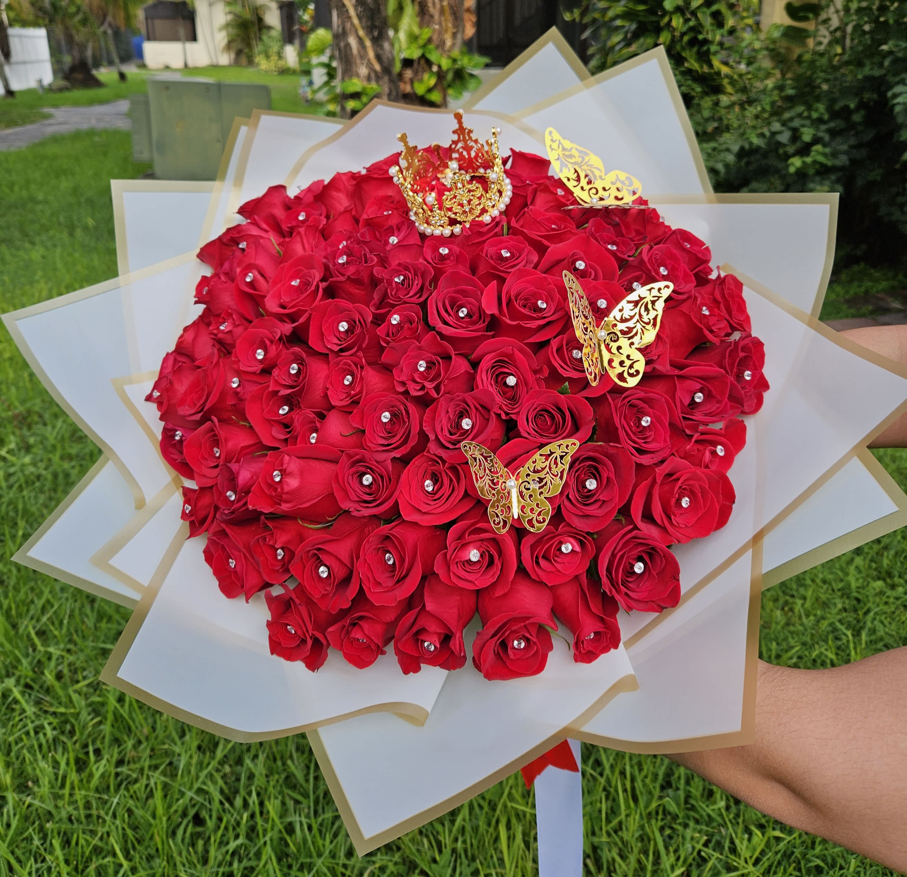 Large bouquet of red roses with gold butterfly decorations and white wrapping