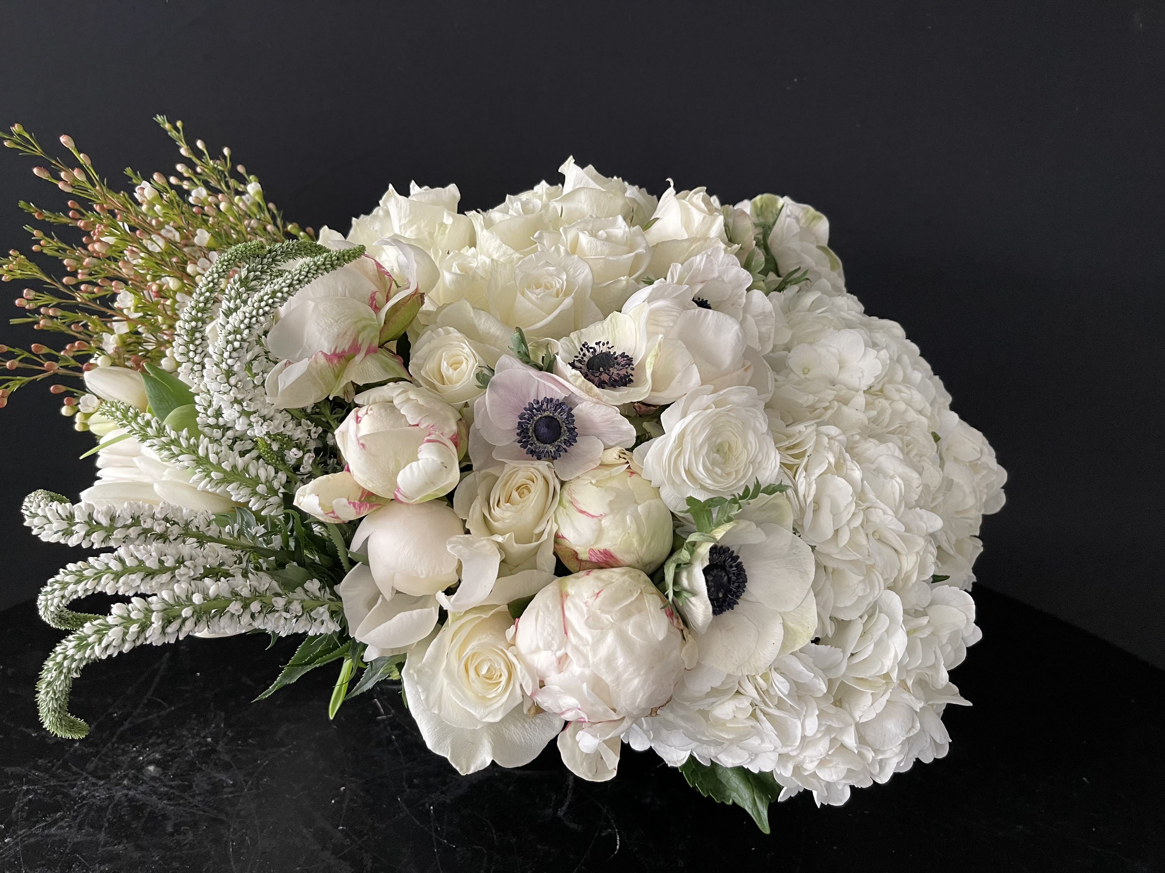 Moms Favorite. - This design will include all white flowers. Some of these flowers may have a some other color like anemones or orchids, but it is what we would consider an all white design.  Upgrade includes peonies and or orchid.  