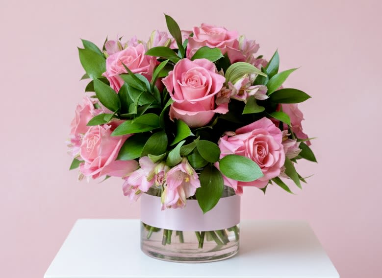 Pink roses arranged in a clear glass vase with green foliage