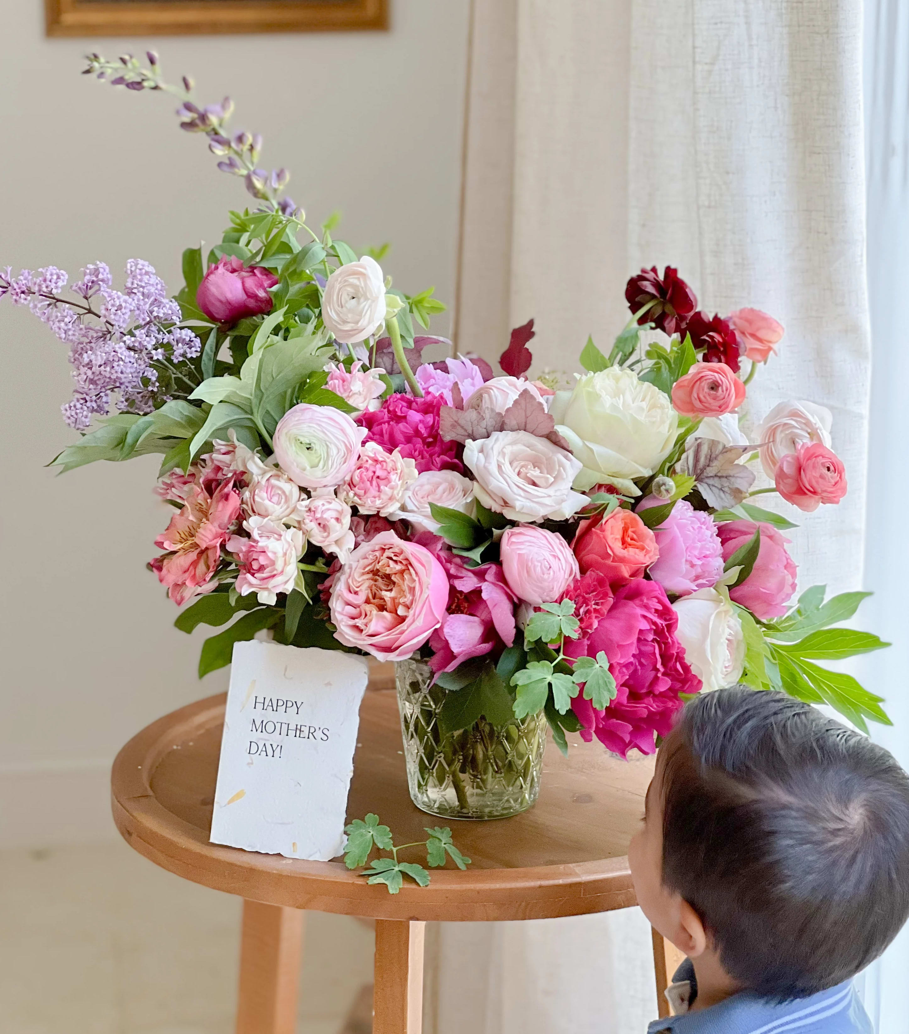 Mixed pink and white flower arrangement in a glass vase with a Mother's Day card