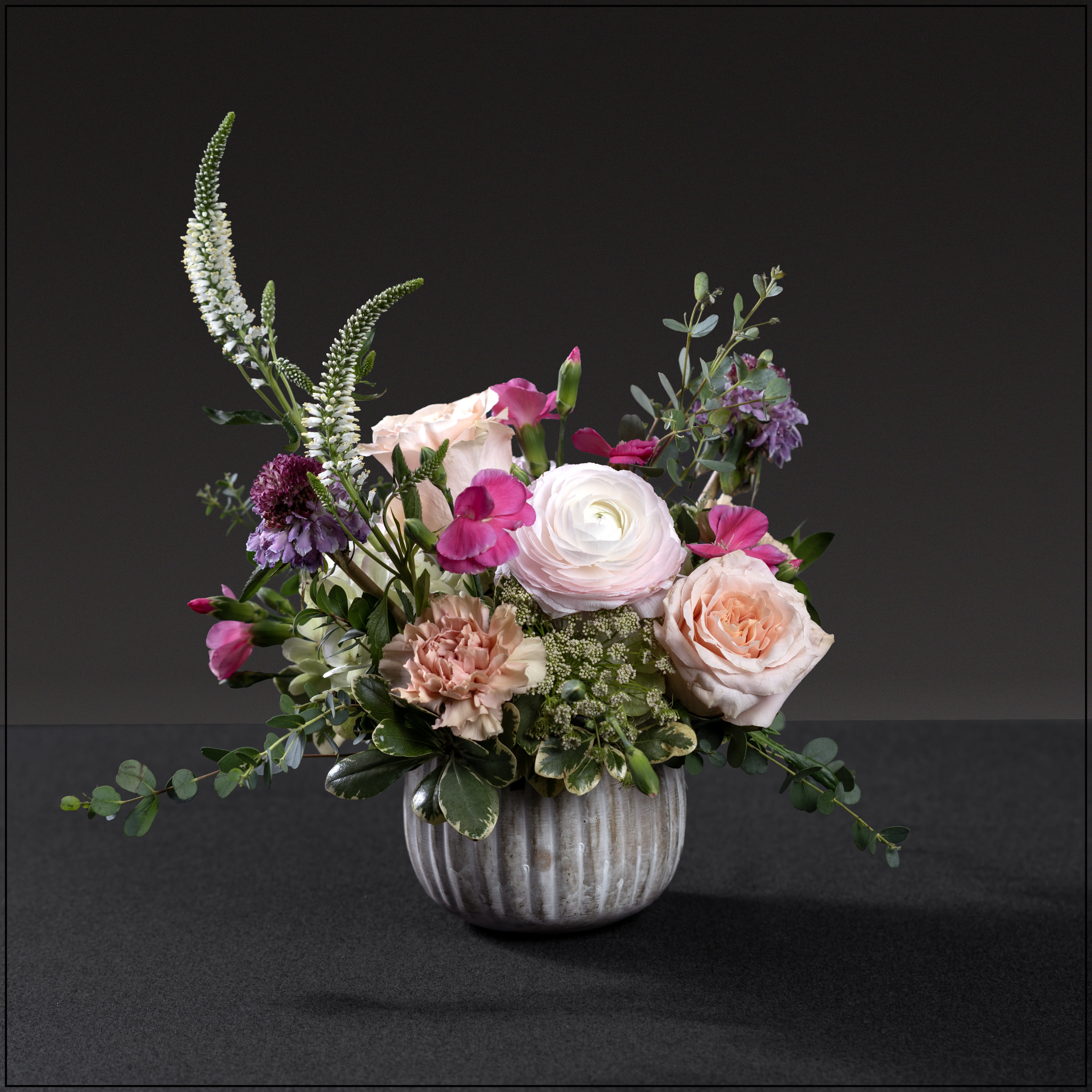 Mom's Cutie - A gorgeous mix of hydrangea, ranunculus, antique carnations, roses, scabiosa, veronica, accented with ammi majus and hot pink solomio, in a larger white-washed gold container.