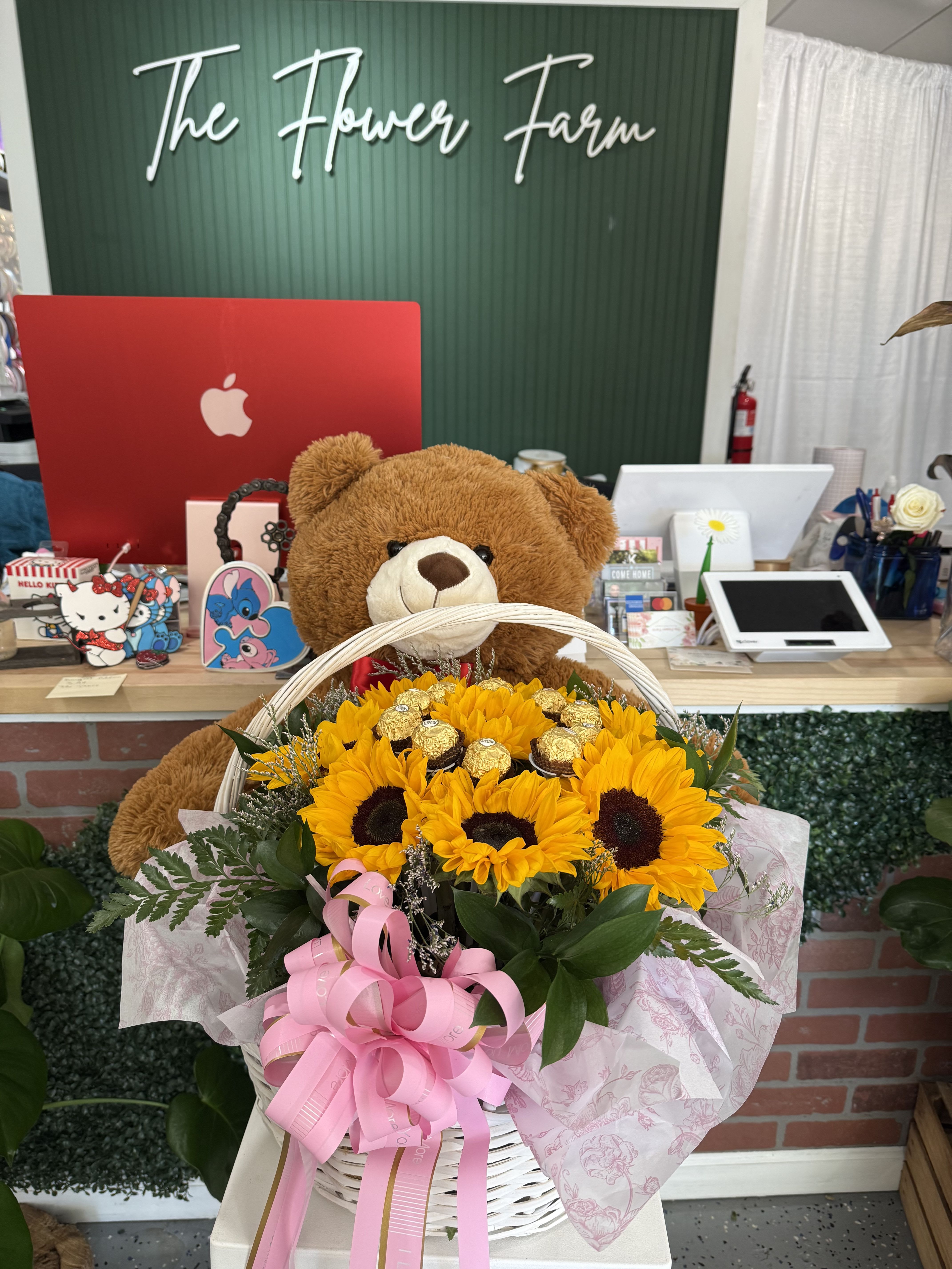 Basket of sunflowers with a teddy bear and pink ribbon