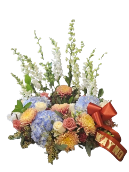 Forever in Bloom Tribute - Celebrate a beautiful life with this vibrant and uplifting urn wreath, thoughtfully designed to honor cherished memories. Featuring a joyful blend of soft blue hydrangea, warm peach and golden blooms, delicate roses, and graceful vertical accents, this arrangement brings light, color, and a sense of peace to any service.  Designed to surround an urn with elegance, this piece symbolizes a life well lived—full of love, warmth, and meaningful moments. The cheerful palette and natural garden style create a comforting presence while celebrating the spirit and legacy of your loved one.  Perfect for memorial services, celebrations of life, or intimate gatherings, this wreath offers a heartfelt tribute filled with beauty and remembrance. Personalized Ribbon add $10.00.