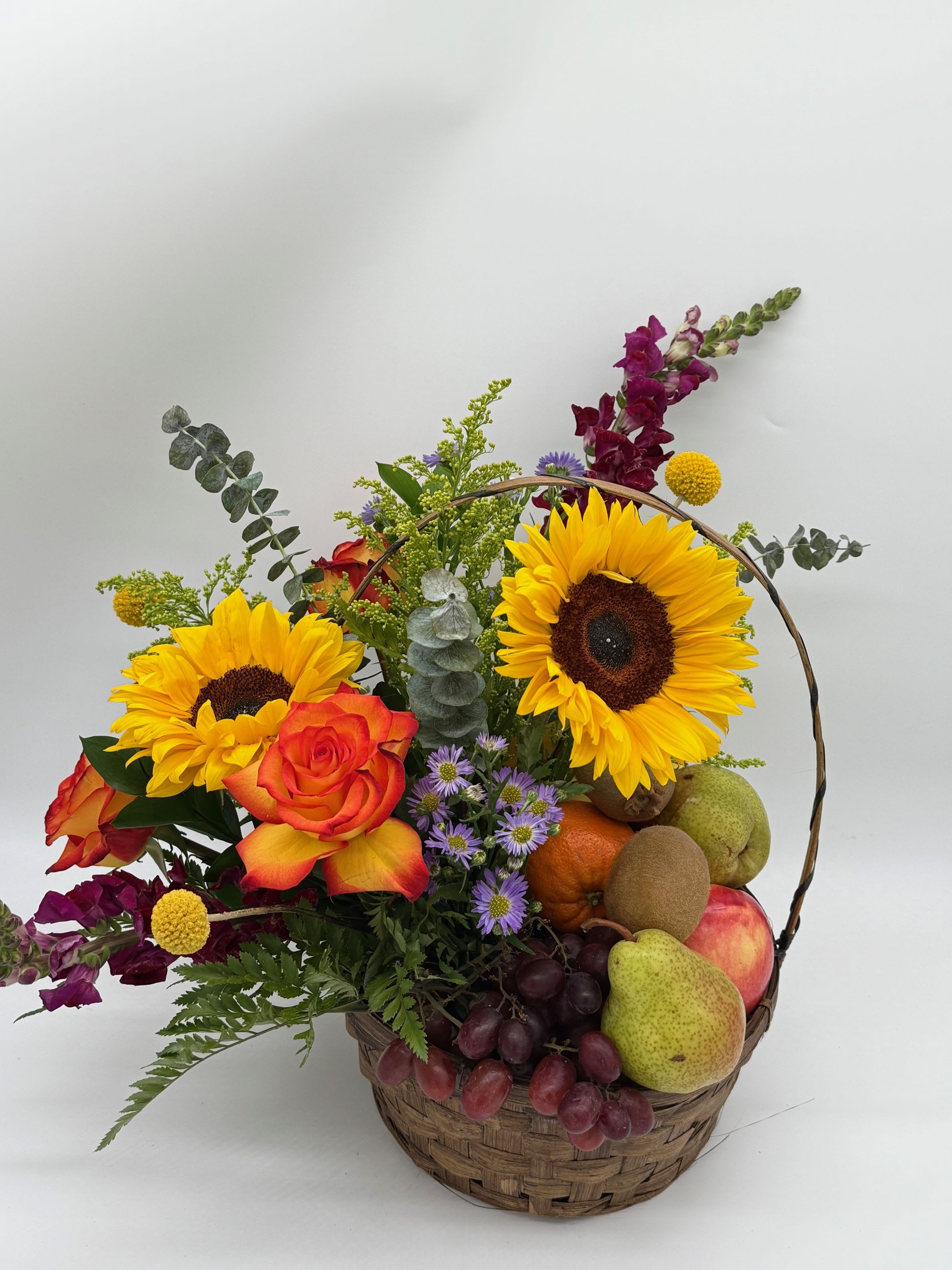 Basket arrangement with sunflowers, roses, grapes, and assorted fruit