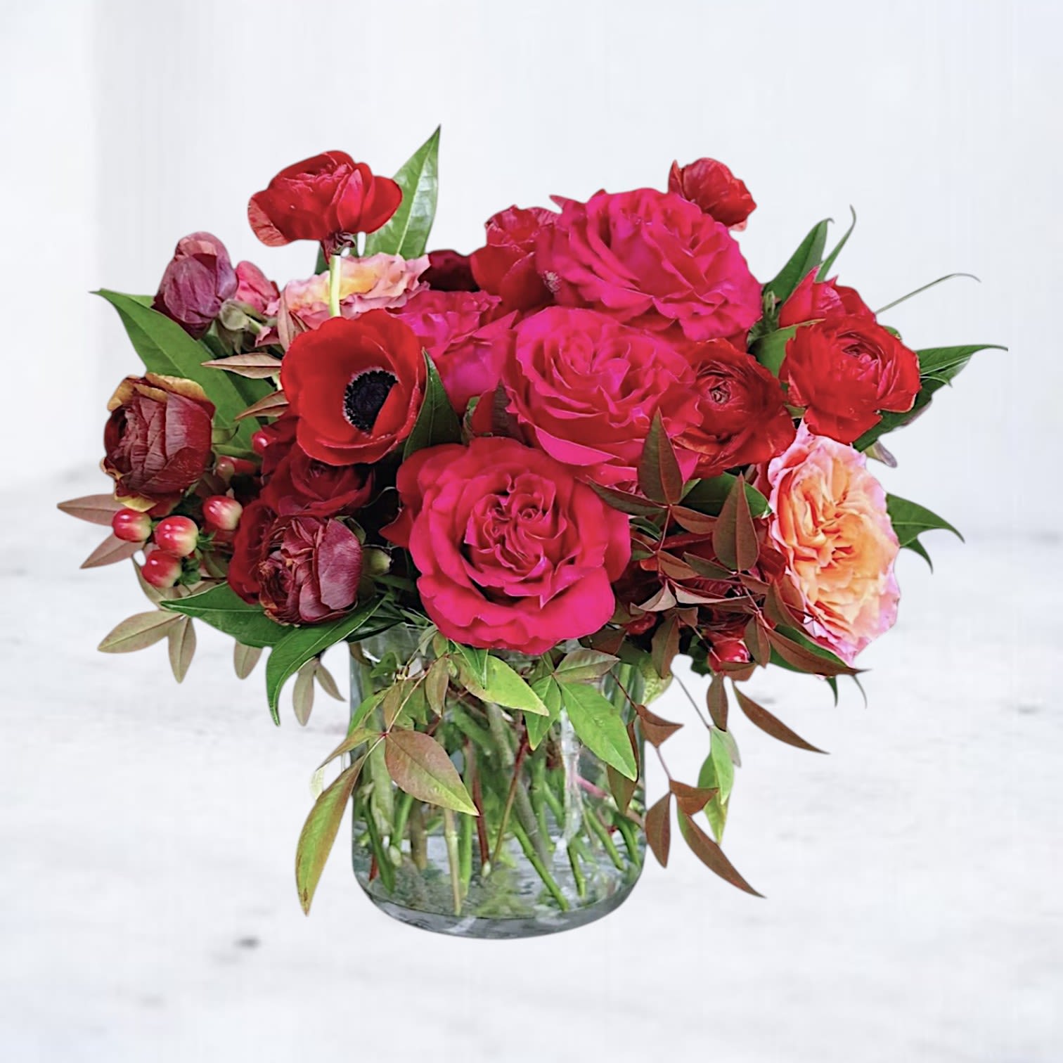 Chateau Rouge - Château Rouge is a rich, romantic floral arrangement designed with depth, texture, and a modern, moody palette. Featuring lush red and fuchsia roses, velvety ranunculus, striking anemones, and seasonal accent blooms, this arrangement is layered with warm-toned foliage and fresh greenery to create a full, dimensional composition. Designed in a clear glass vase, Château Rouge blends bold color with organic movement, offering a refined, editorial take on classic red florals. The interplay of deep crimson, berry tones, and soft peach accents adds complexity and warmth, making this arrangement feel both luxurious and intentionally designed.  Perfect for anniversaries, romantic gestures, Valentine’s Day, or meaningful “just because” moments, this elevated red flower arrangement delivers a dramatic yet sophisticated statement that goes far beyond traditional dozen roses. Same-day flower delivery is available in Magnolia, TX, The Woodlands, Montgomery, Conroe, Spring, Tomball, and surrounding North Houston areas.  Due to seasonal availability, some blooms may be replaced with similar varieties of equal or greater value to maintain the design’s look and integrity. Your arrangement will always reflect the same color palette, style, and premium quality