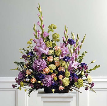 Large mixed floral arrangement in a low black container with purple, pink, and peach blooms
