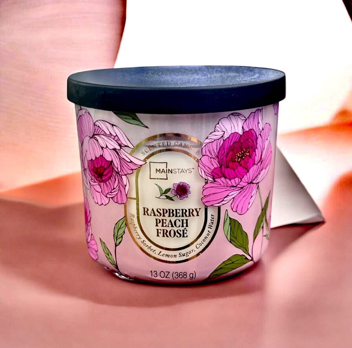 Pink floral scented candle in a black-lidded jar