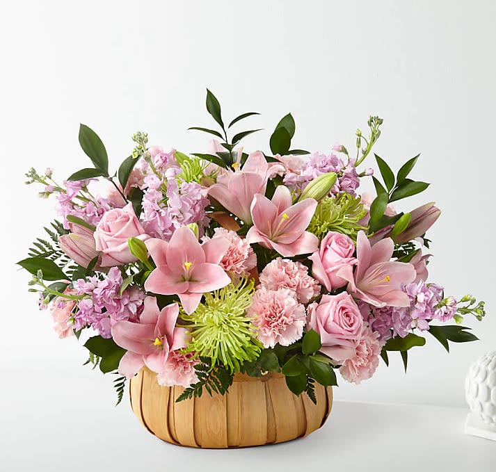 Pink lilies, roses, and carnations in a pumpkin-shaped basket